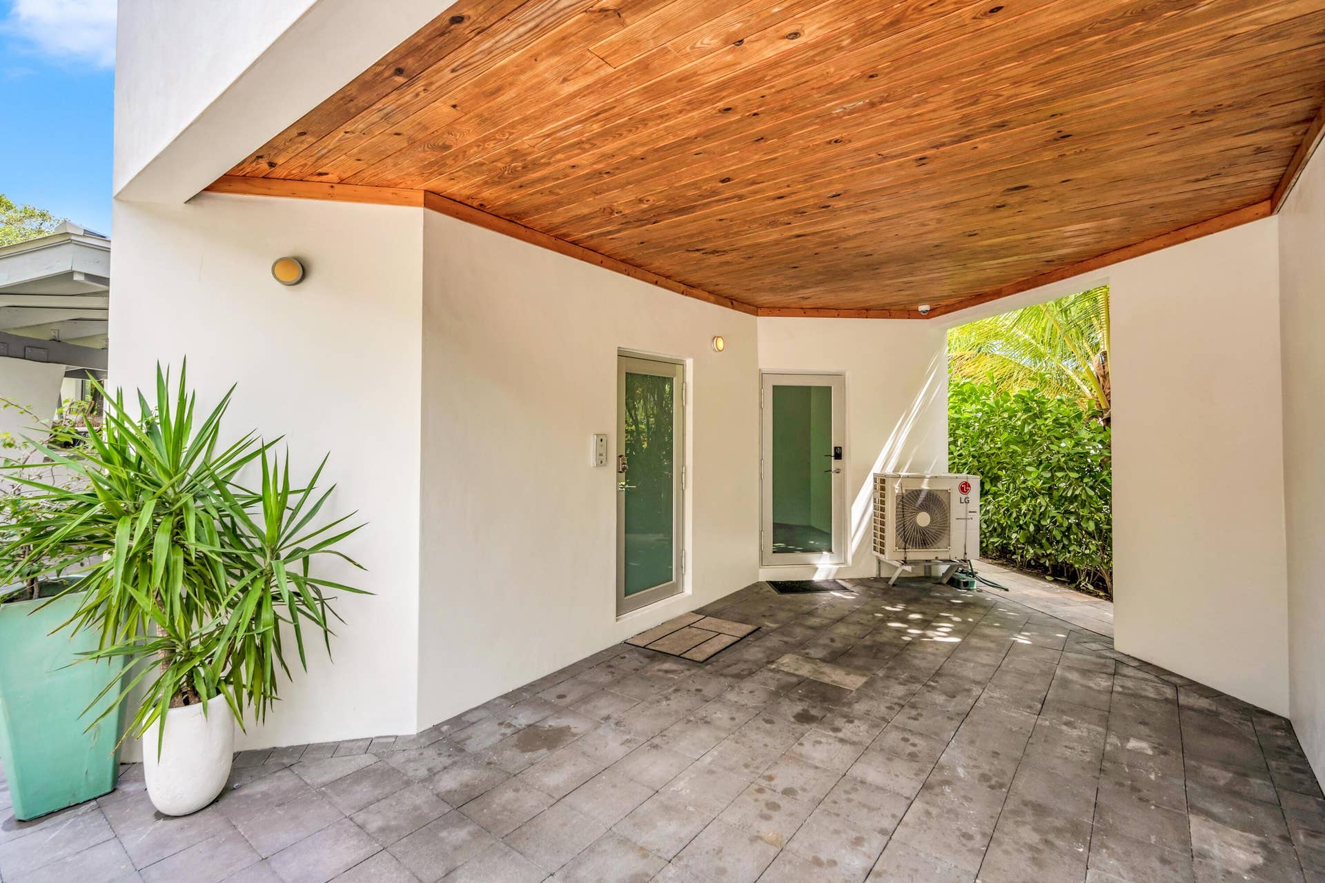 510 SW 18th Avenue, Fort Lauderdale, FL 33312 Covered patio featuring a wood-finish ceiling, light gray paver flooring, white stucco walls, and two exterior doors with frosted glass panels