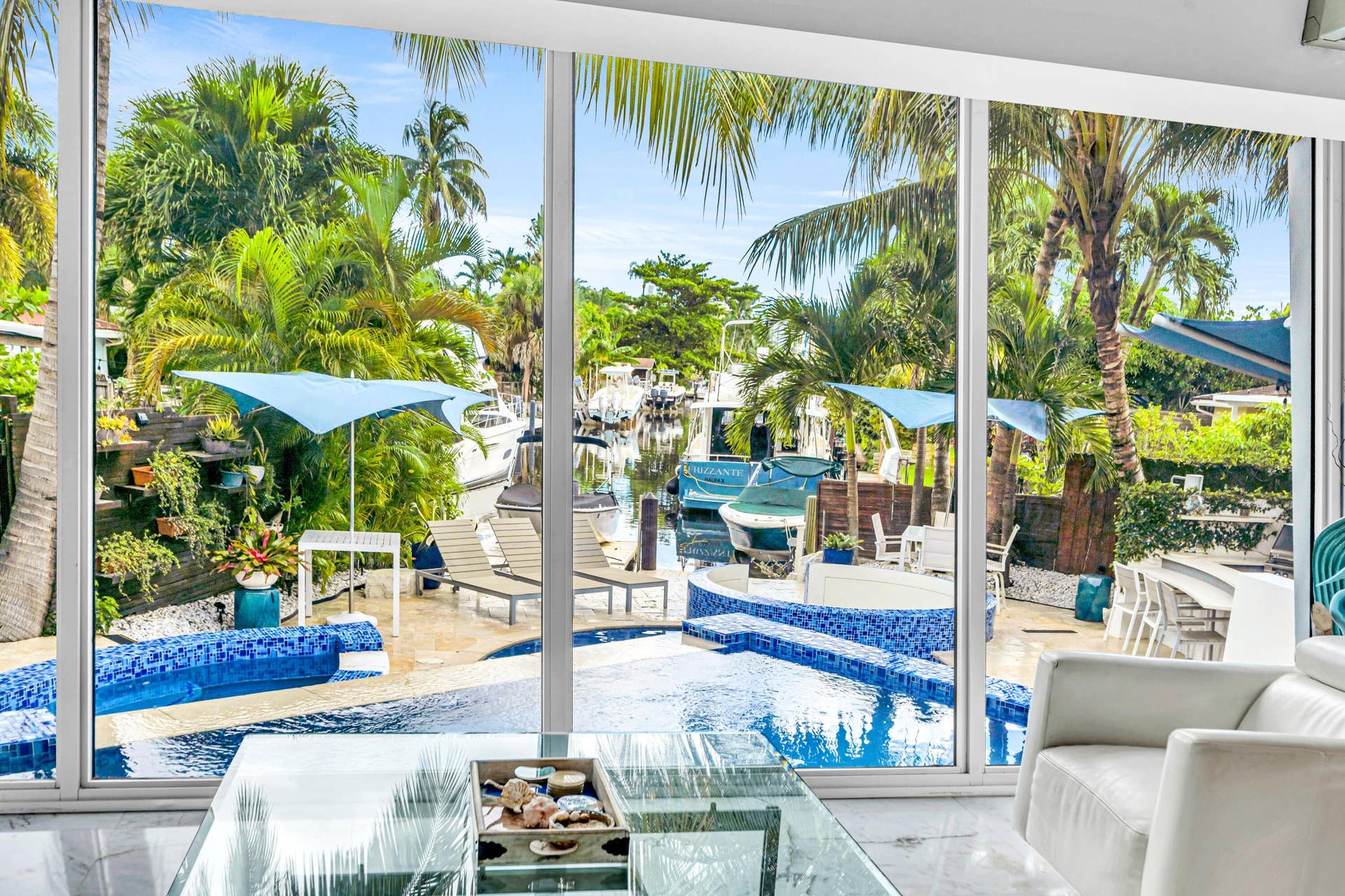 510 SW 18th Avenue, Fort Lauderdale, FL 33312 Floor-to-ceiling windows with expansive water frontage, a built-in pool, and a spa featuring blue mosaic tile