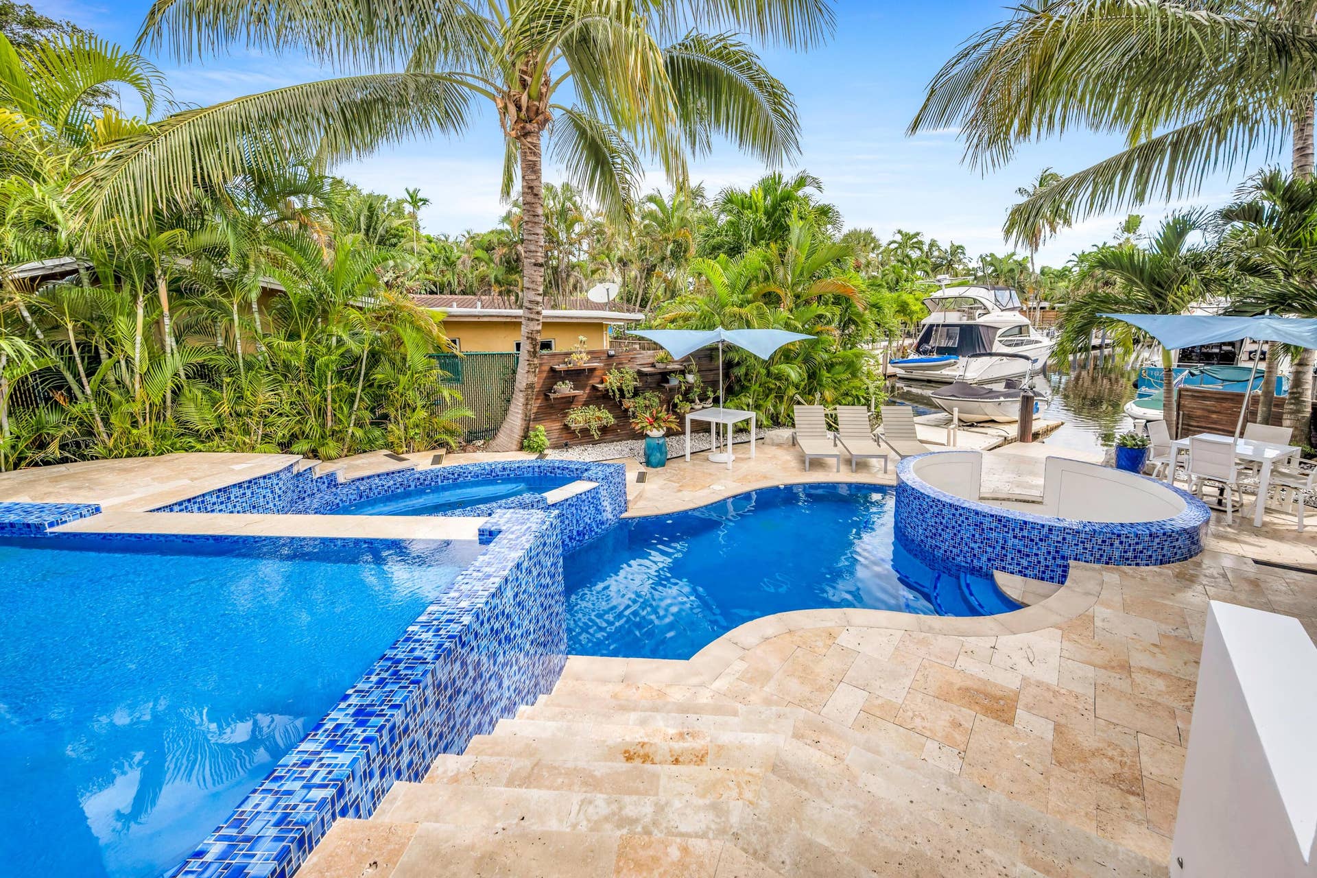 510 SW 18th Avenue, Fort Lauderdale, FL 33312 Multi-level swimming pool with blue mosaic tile accents, integrated spa, travertine paver decking, and lush tropical landscaping