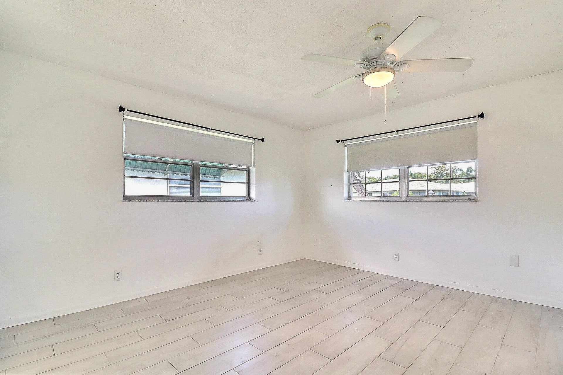 450 BLUEBIRD Lane, Delray Beach, FL 33445 Recessed windows with roller shades, a ceiling fan with integrated lighting, and wood-finish flooring