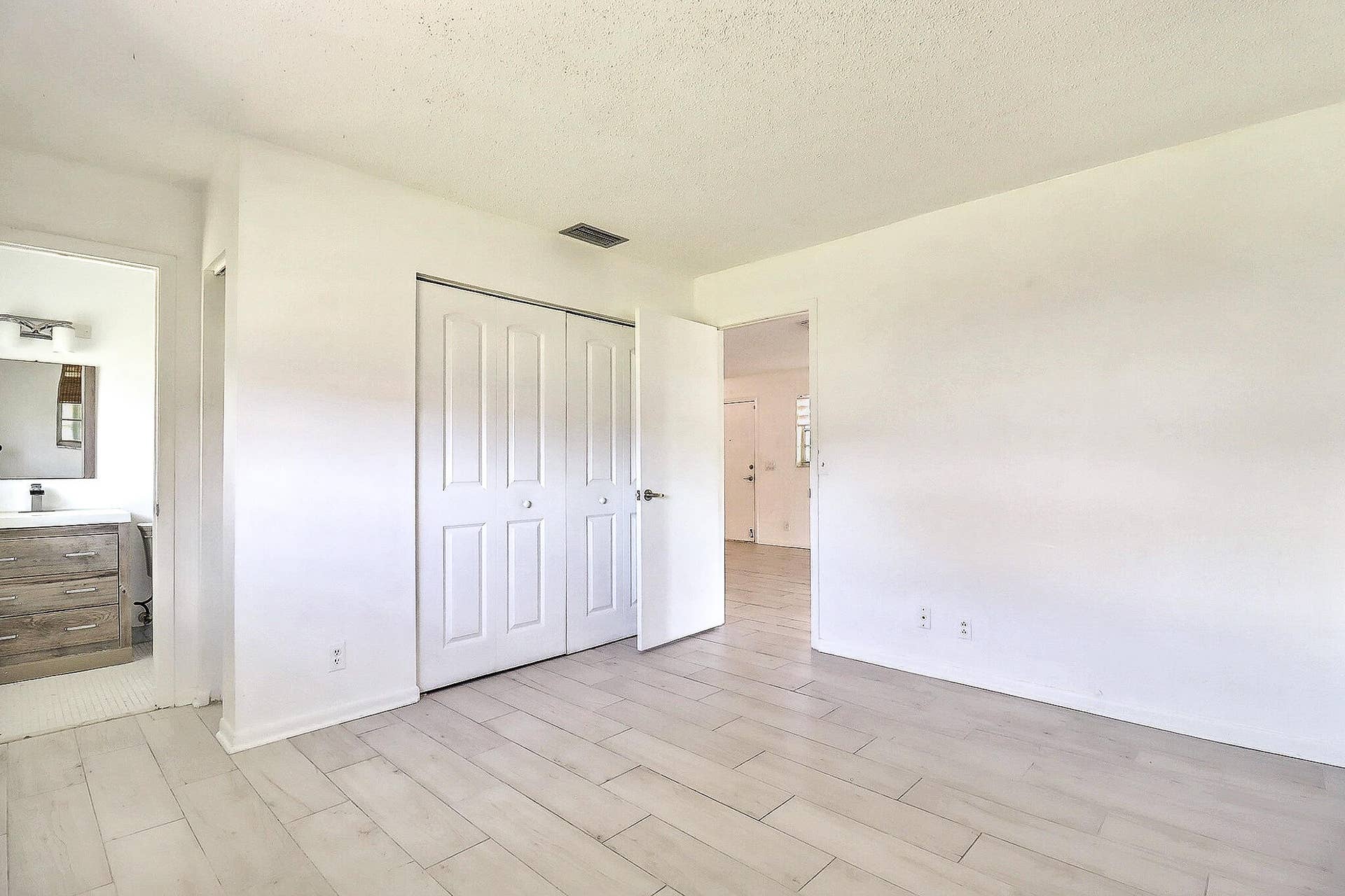 450 BLUEBIRD Lane, Delray Beach, FL 33445 Room featuring light wood-finish flooring, white walls, and a built-in closet with bi-fold doors