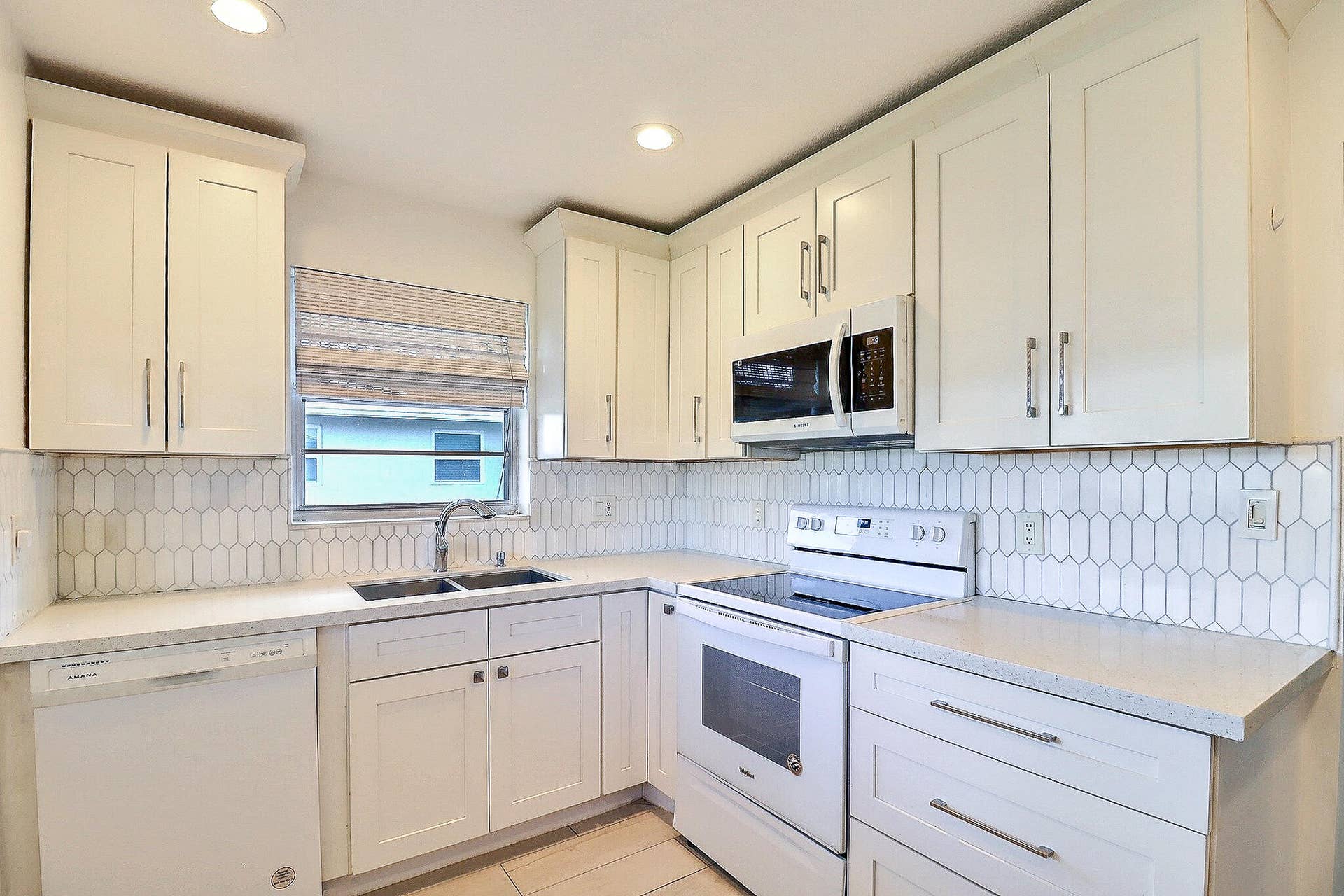 450 BLUEBIRD Lane, Delray Beach, FL 33445 White shaker cabinetry with bar pulls, white appliance package, solid surface countertops, dual basin stainless steel sink, and a picket tile backsplash