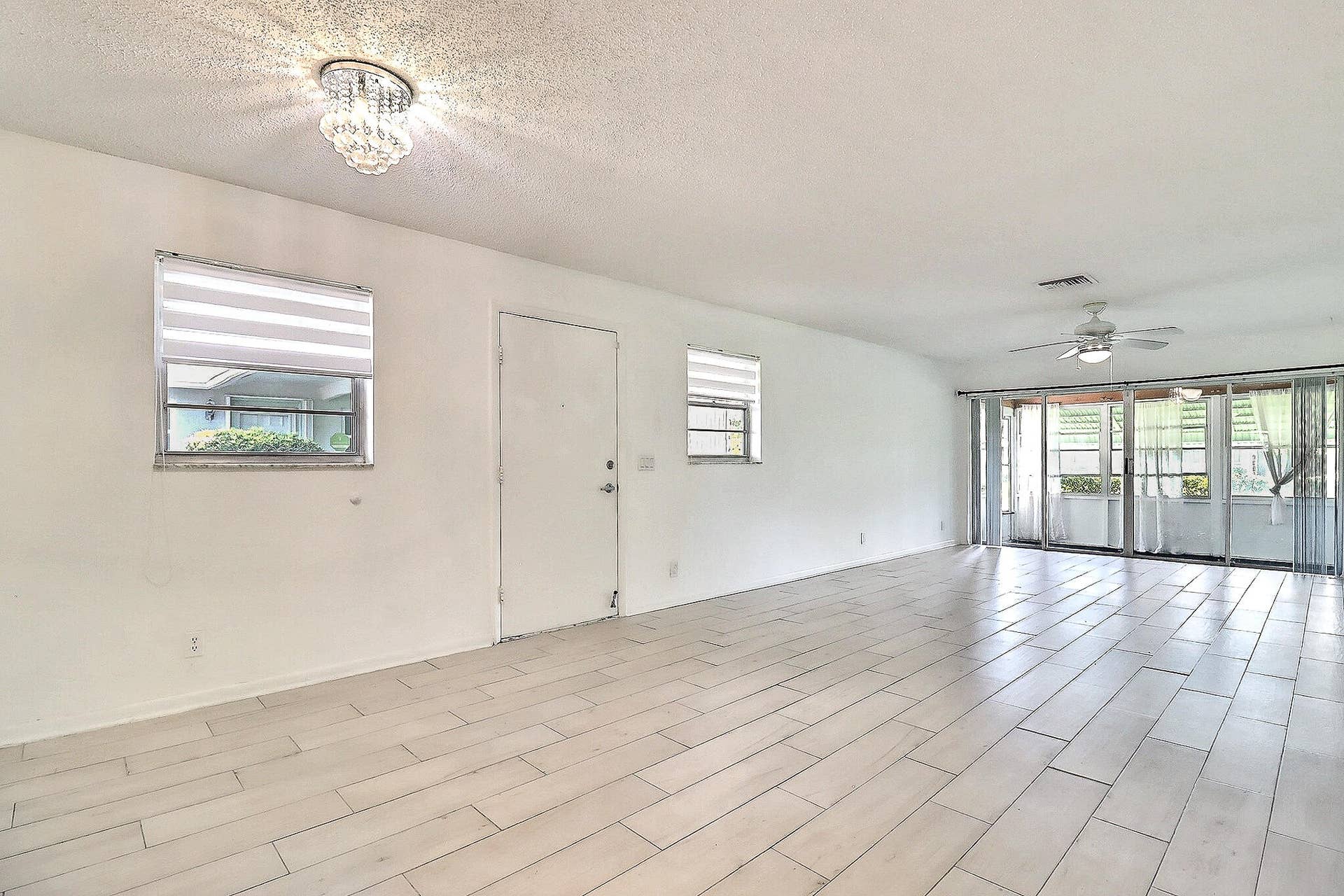 450 BLUEBIRD Lane, Delray Beach, FL 33445 Expansive living space featuring wood-finish tile flooring, a crystal flush mount ceiling light, and a ceiling fan with integrated lighting