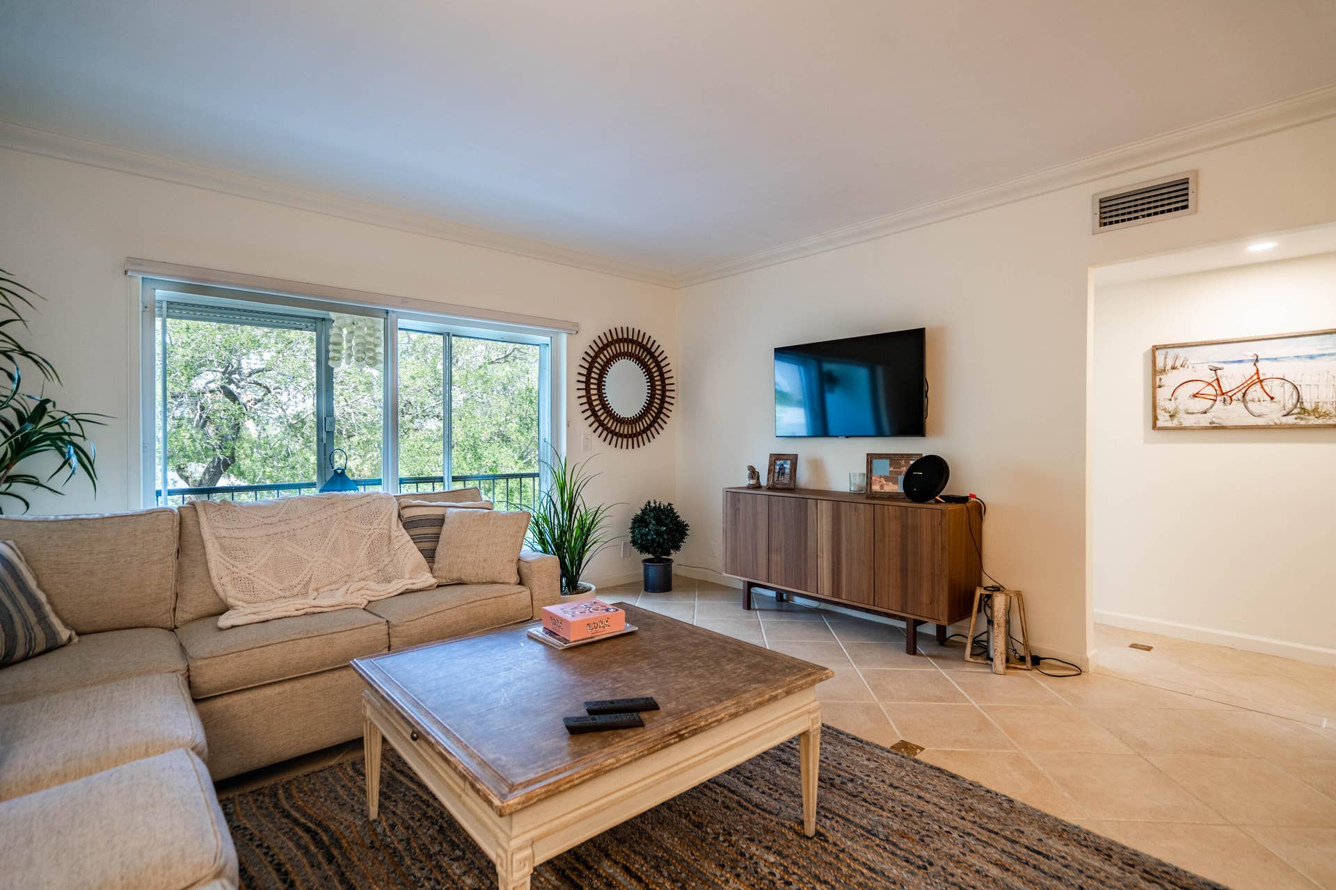 Spacious living area featuring large sliding glass doors, crown molding, and tiled flooring