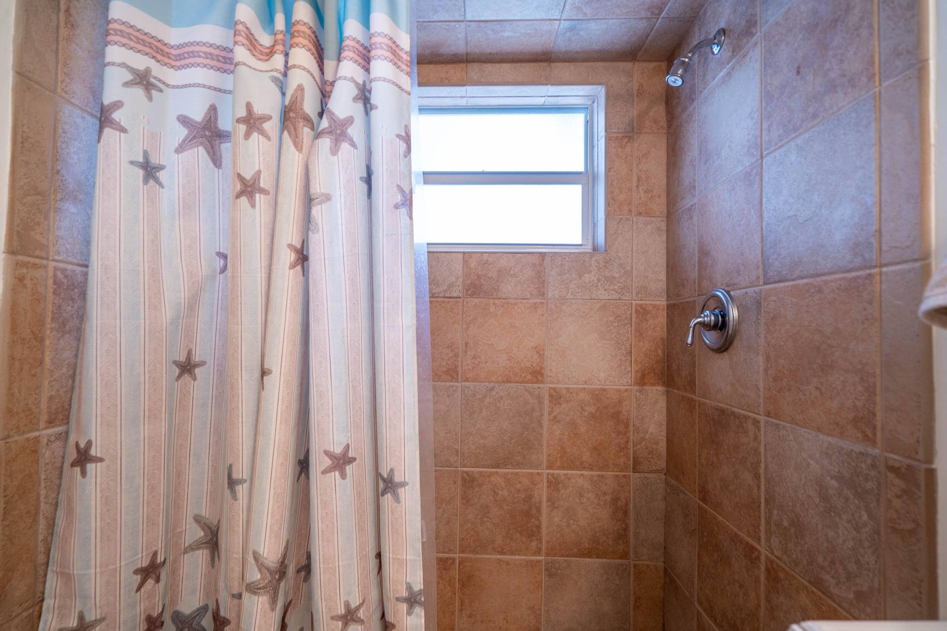 Tiled shower surround with a fixed window and a brushed nickel shower head and faucet