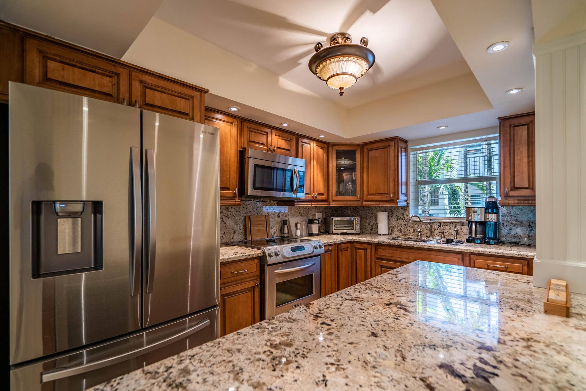 Kitchen featuring wood cabinetry, stainless steel appliances, recessed lighting, and stone countertops