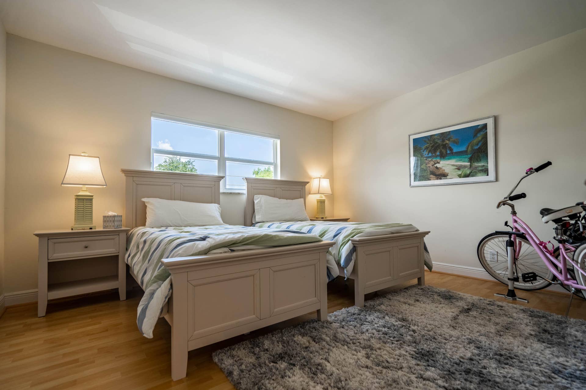 Wood-finish flooring with a large area rug, a window with exterior views, and neutral painted walls
