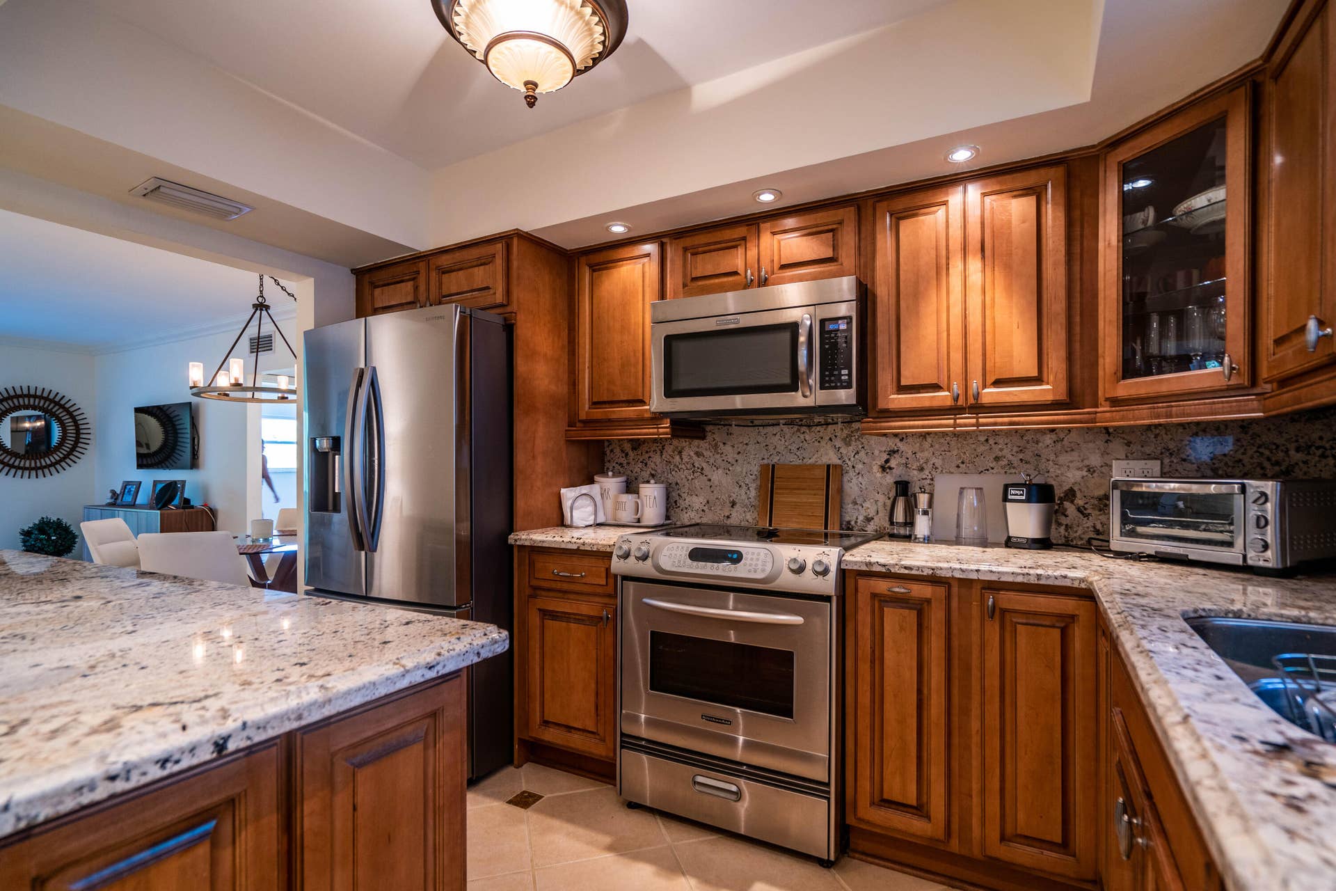 Stainless steel appliances, recessed lighting, wood cabinetry, stone countertops, and tile flooring