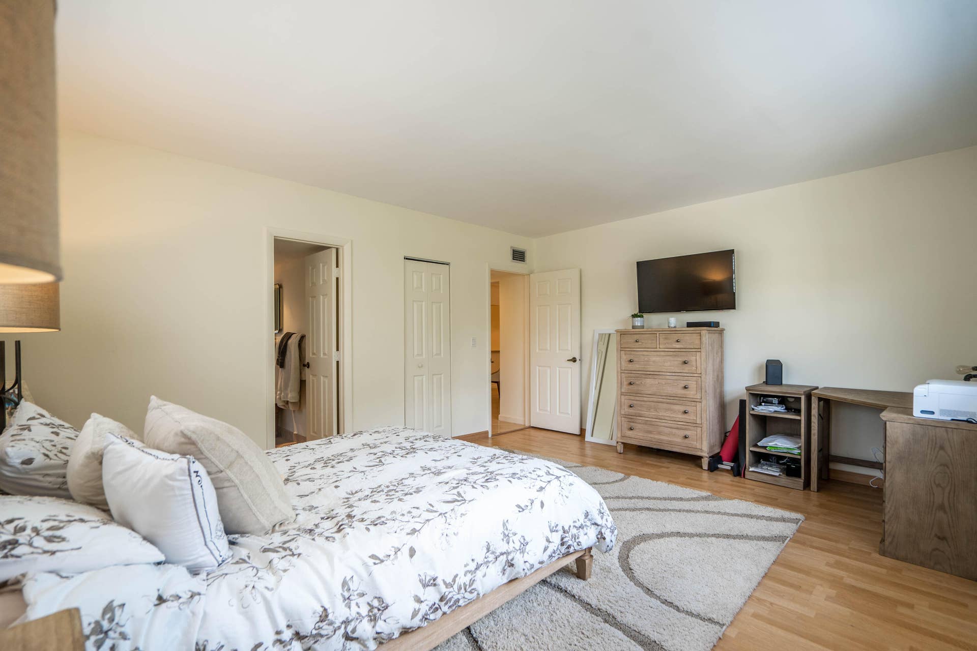 Spacious primary bedroom featuring hardwood flooring, multiple closet access points, and ample natural light