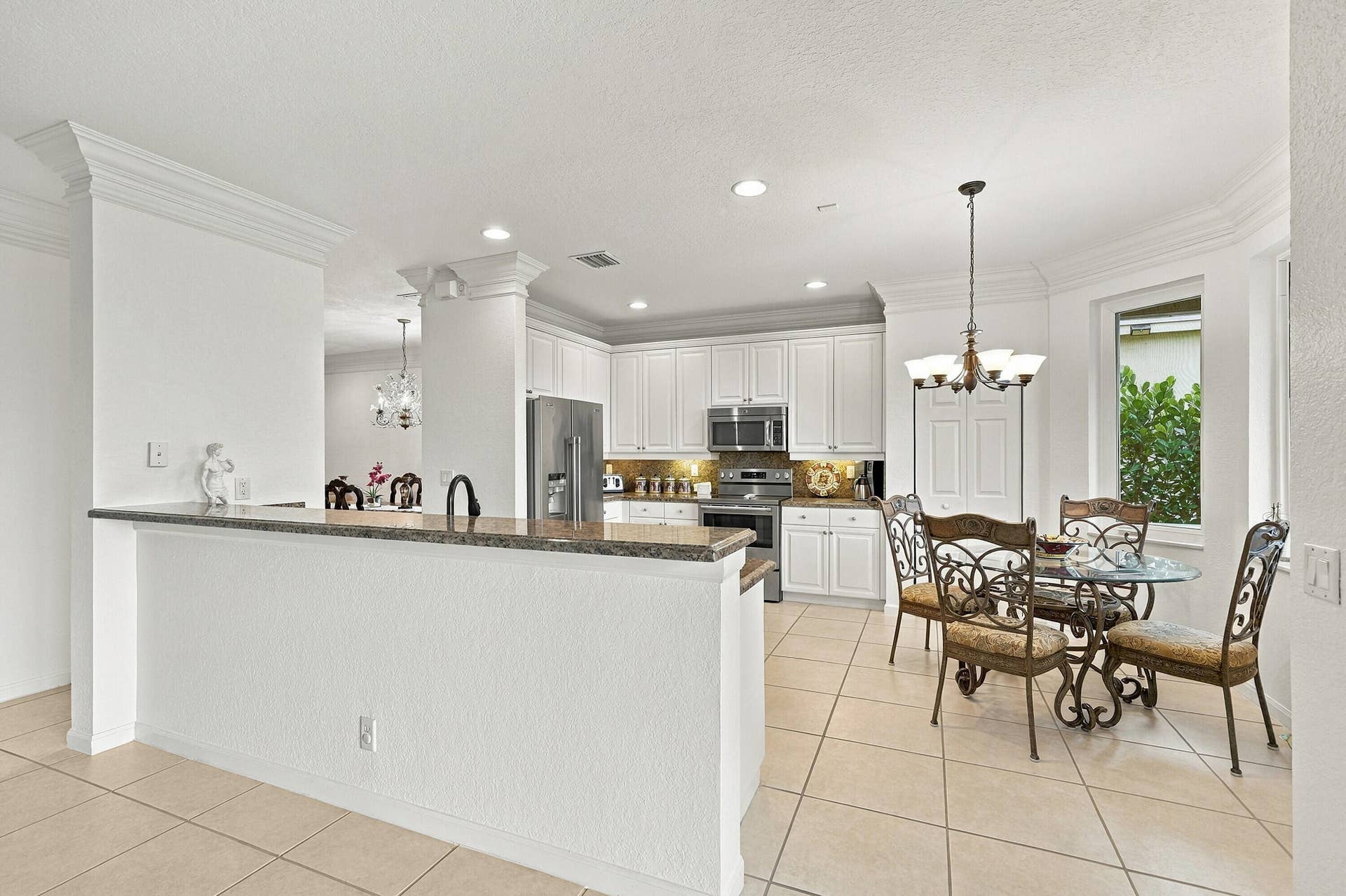 1020 Lavender Circle, Weston, FL 33327 Kitchen and dining area featuring white cabinetry, stainless steel appliances, a breakfast bar with a stone countertop, and tile flooring