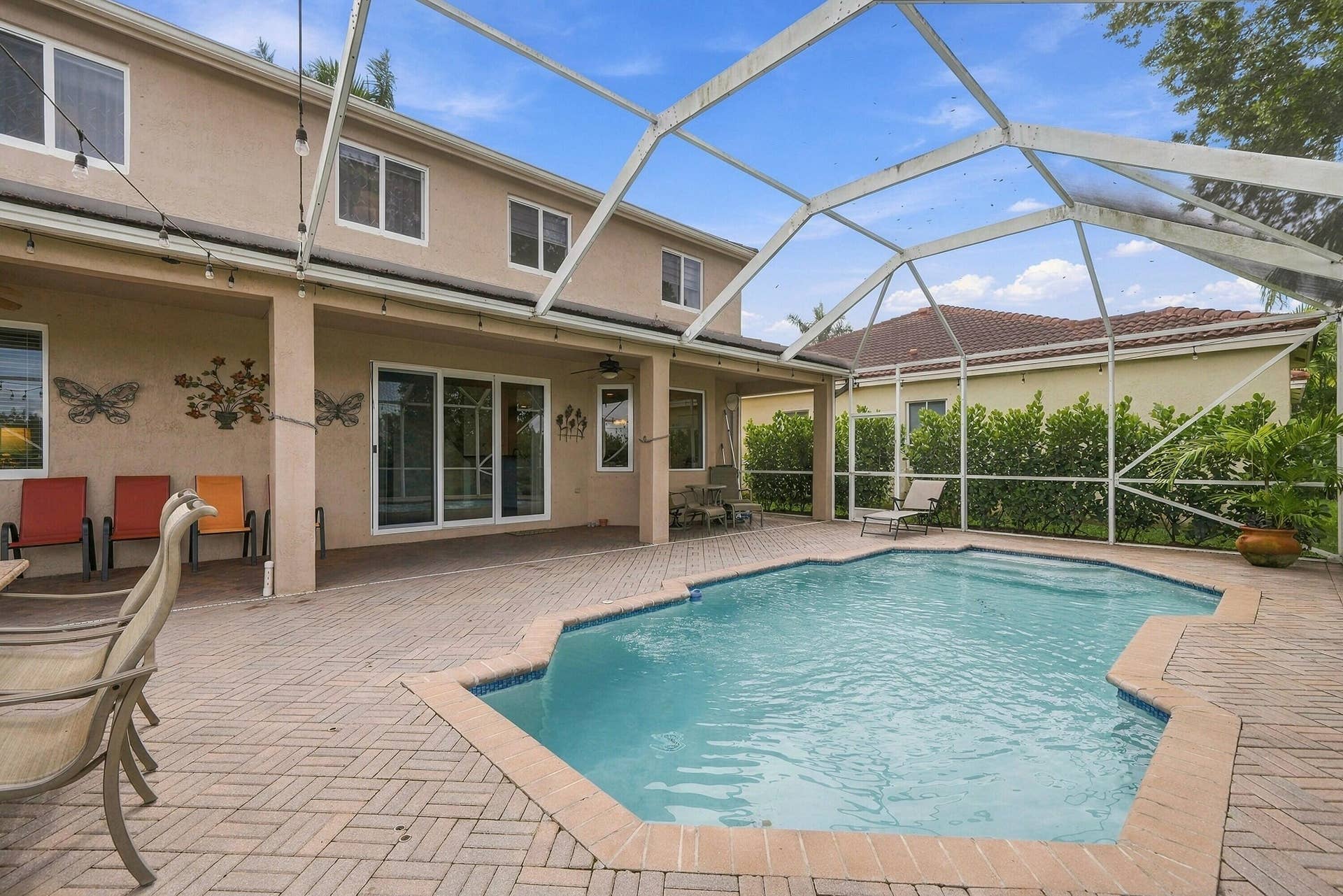 1020 Lavender Circle, Weston, FL 33327 Expansive screened-in pool area featuring a freeform pool, brick paver decking, and a covered patio with sliding glass doors