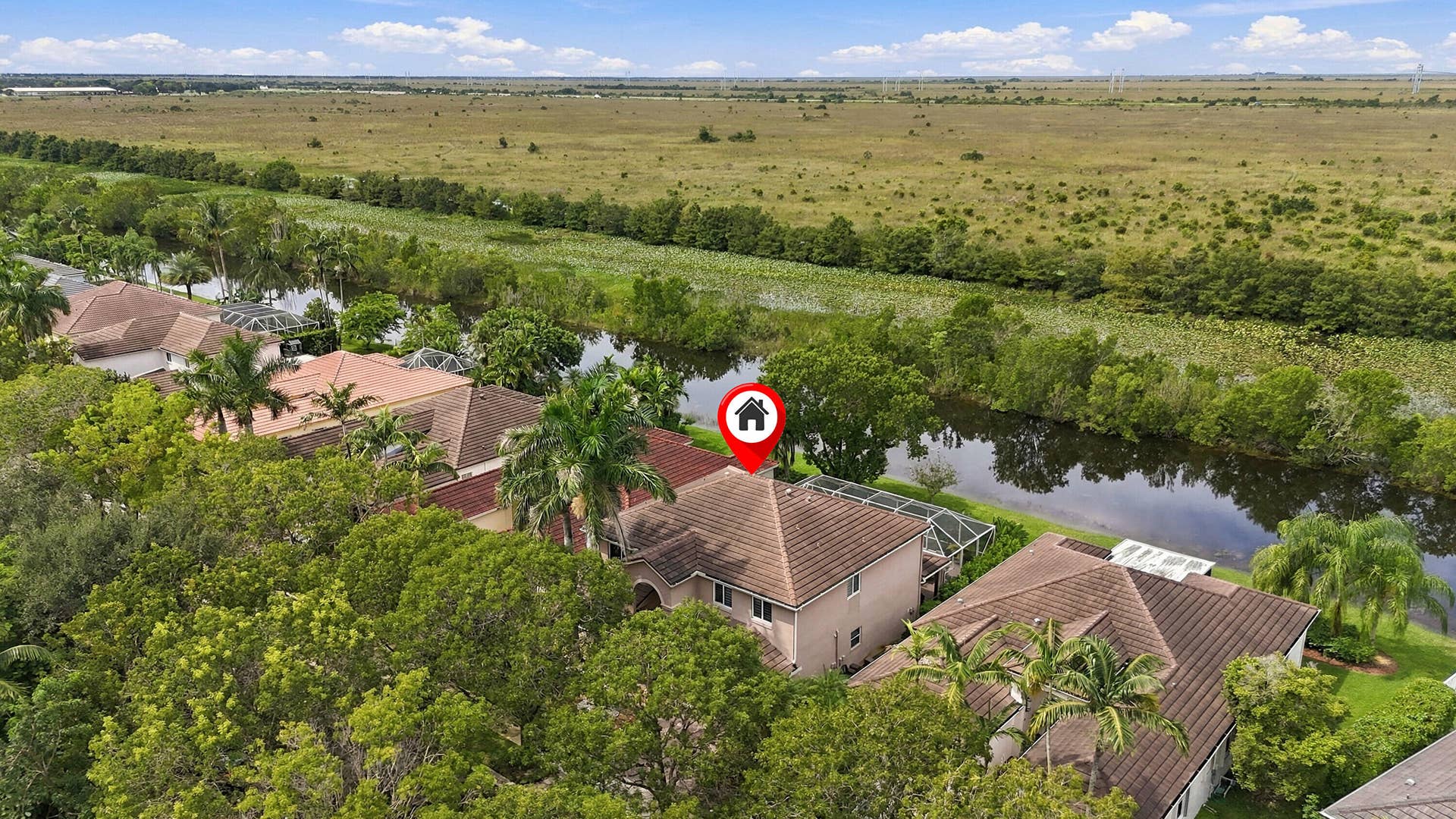1020 Lavender Circle, Weston, FL 33327 Terracotta tile roof with a screened enclosure and mature landscaping, bordering a natural waterway