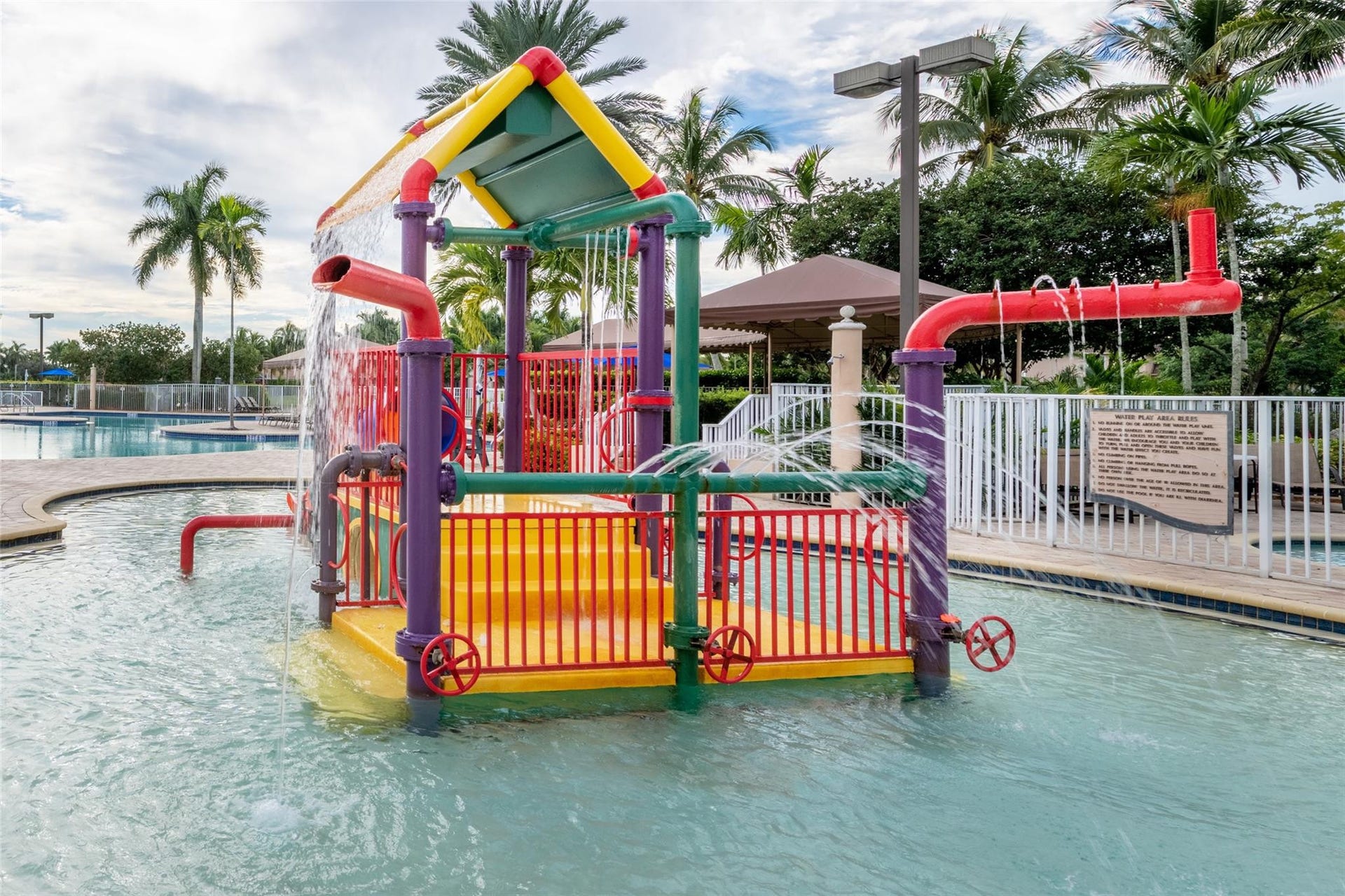1020 Lavender Circle, Weston, FL 33327 Shallow water splash pad with vibrant play structure and active water features, surrounded by a paved deck and fencing