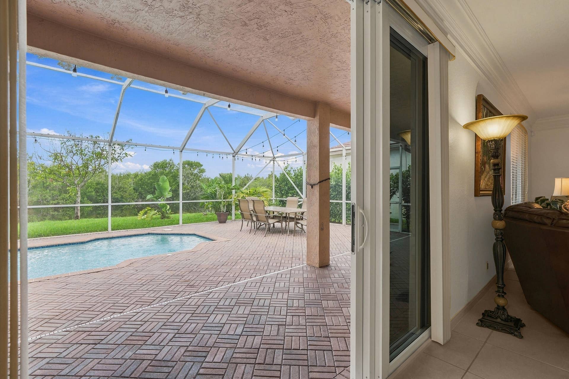 1020 Lavender Circle, Weston, FL 33327 Expansive screened-in lanai with a freeform swimming pool, paver deck, and covered patio