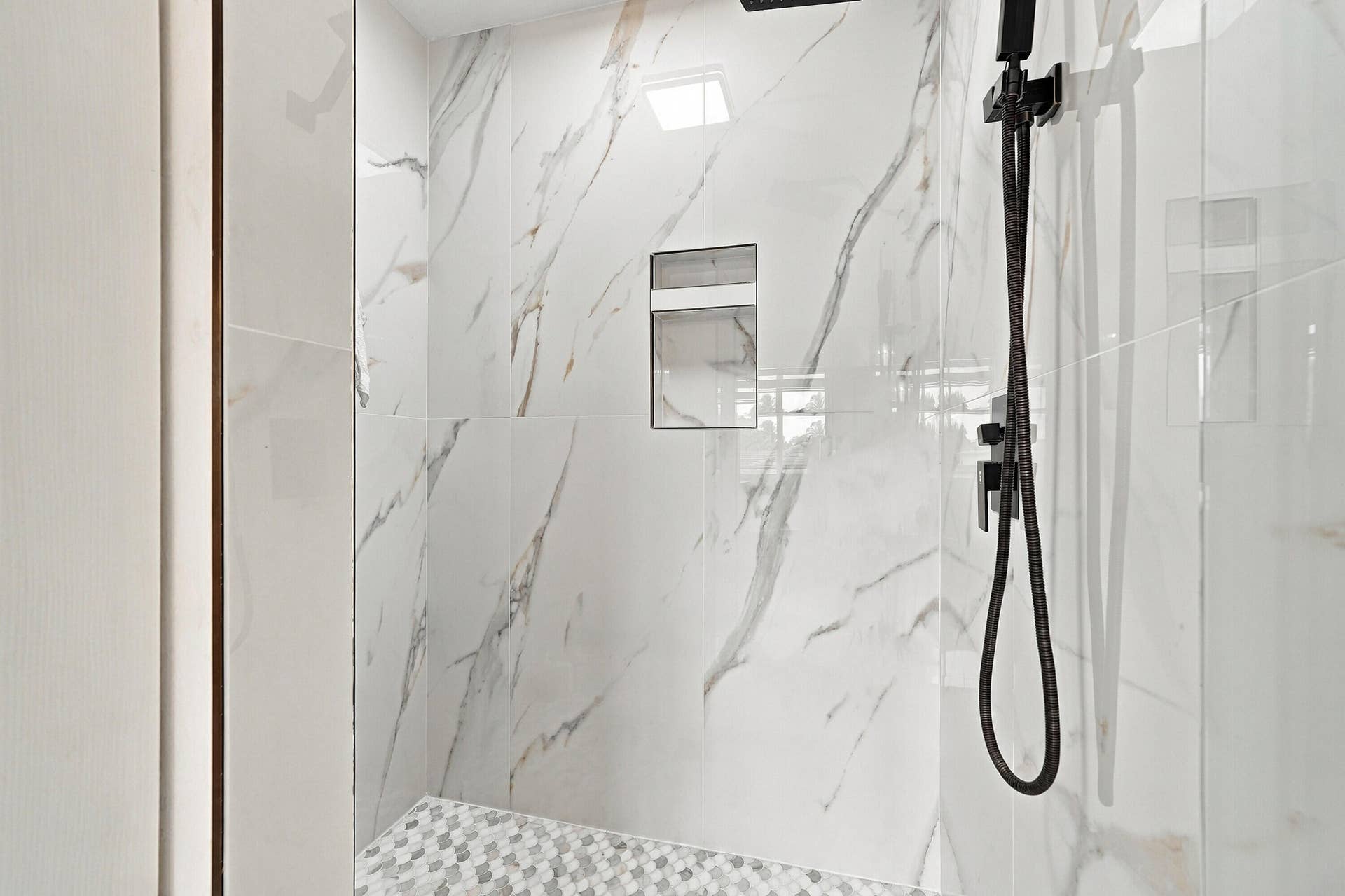1020 Lavender Circle, Weston, FL 33327 Shower with marble-finish walls, geometric mosaic tile flooring, built-in recessed shelf, and matte black shower fixtures