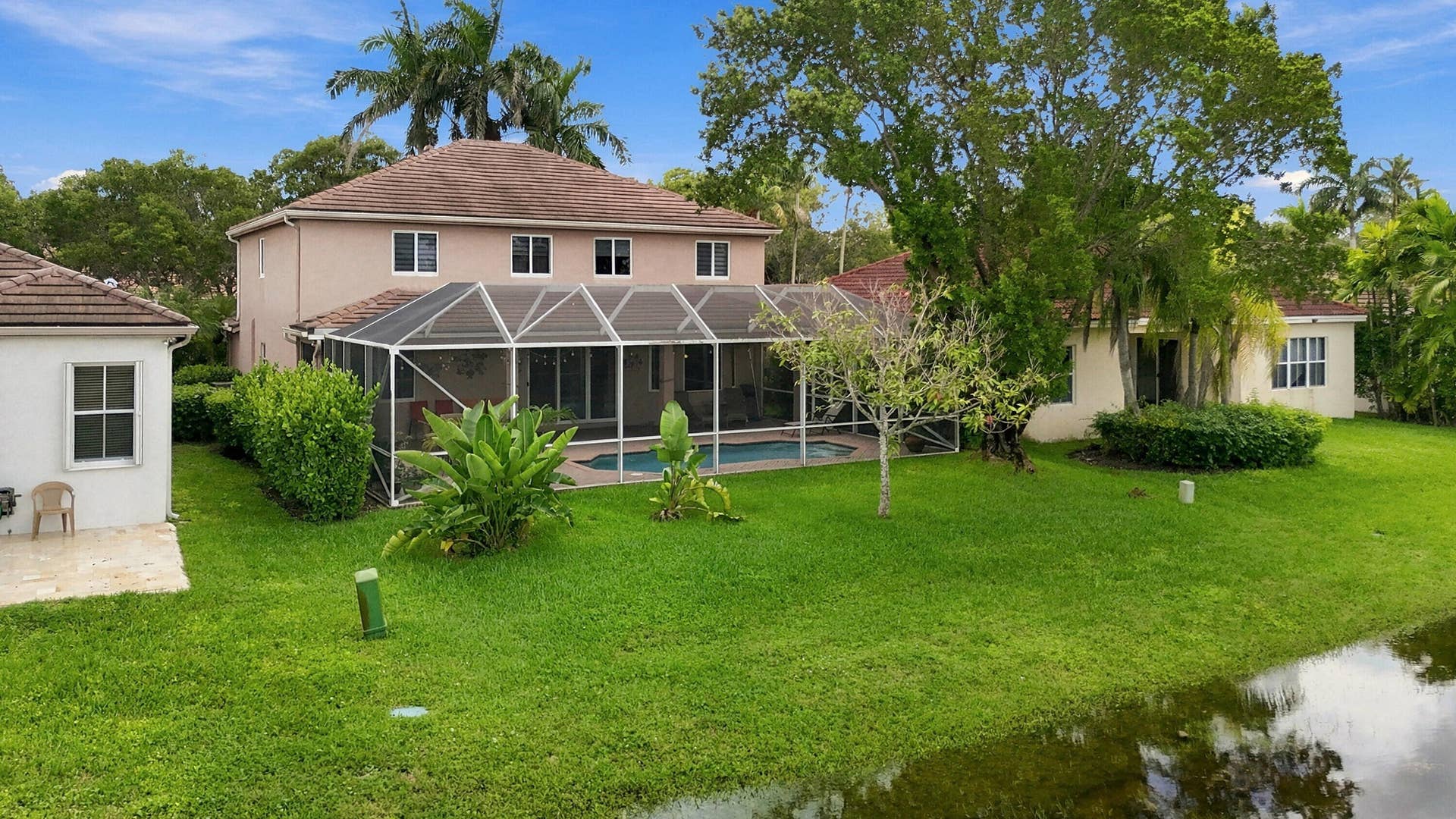 1020 Lavender Circle, Weston, FL 33327 Expansive backyard featuring a screened-in swimming pool, a separate detached structure, and mature landscaping