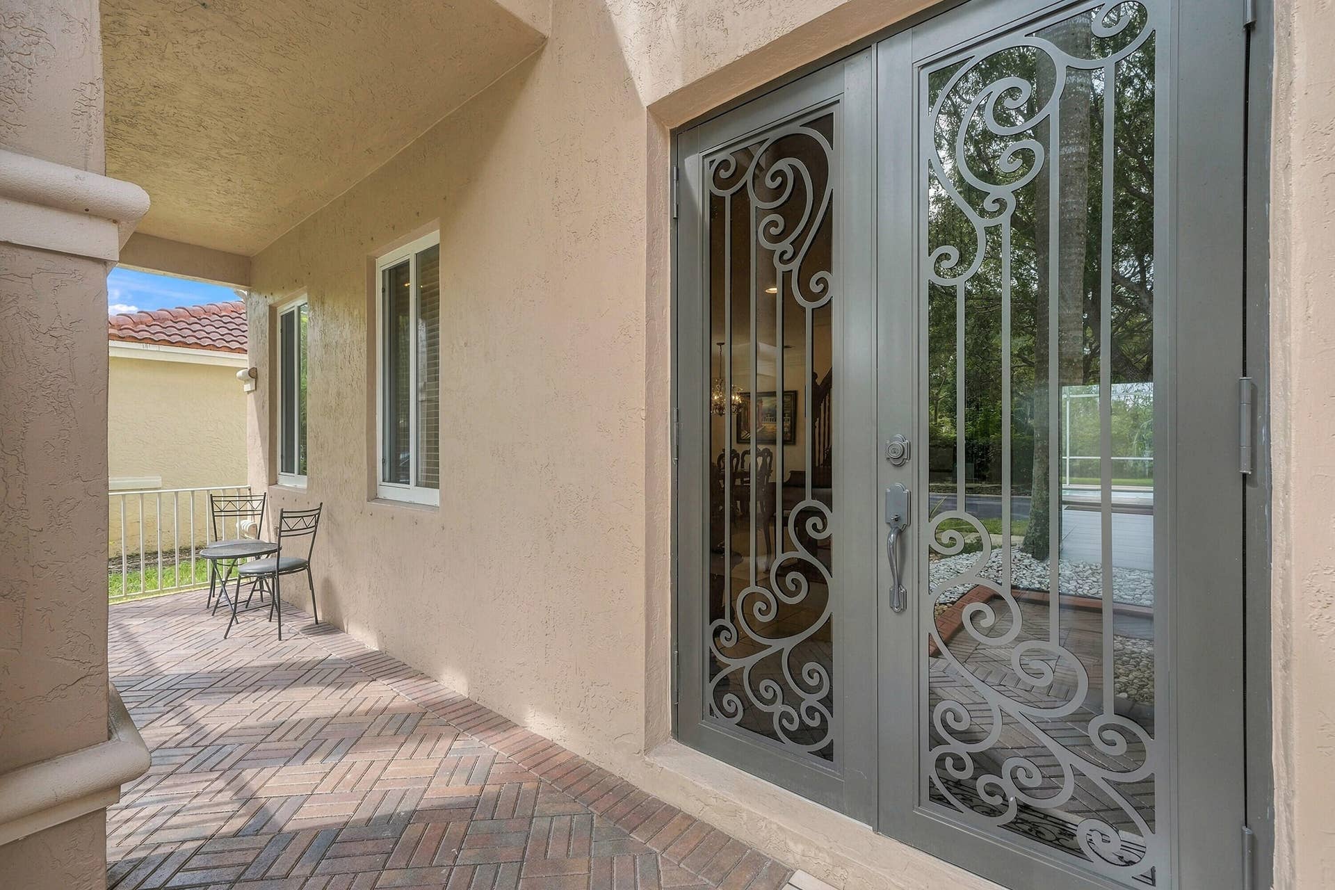1020 Lavender Circle, Weston, FL 33327 Stucco exterior with a covered entry, decorative double-door entry, rectangular windows, and a brick-patterned paver patio