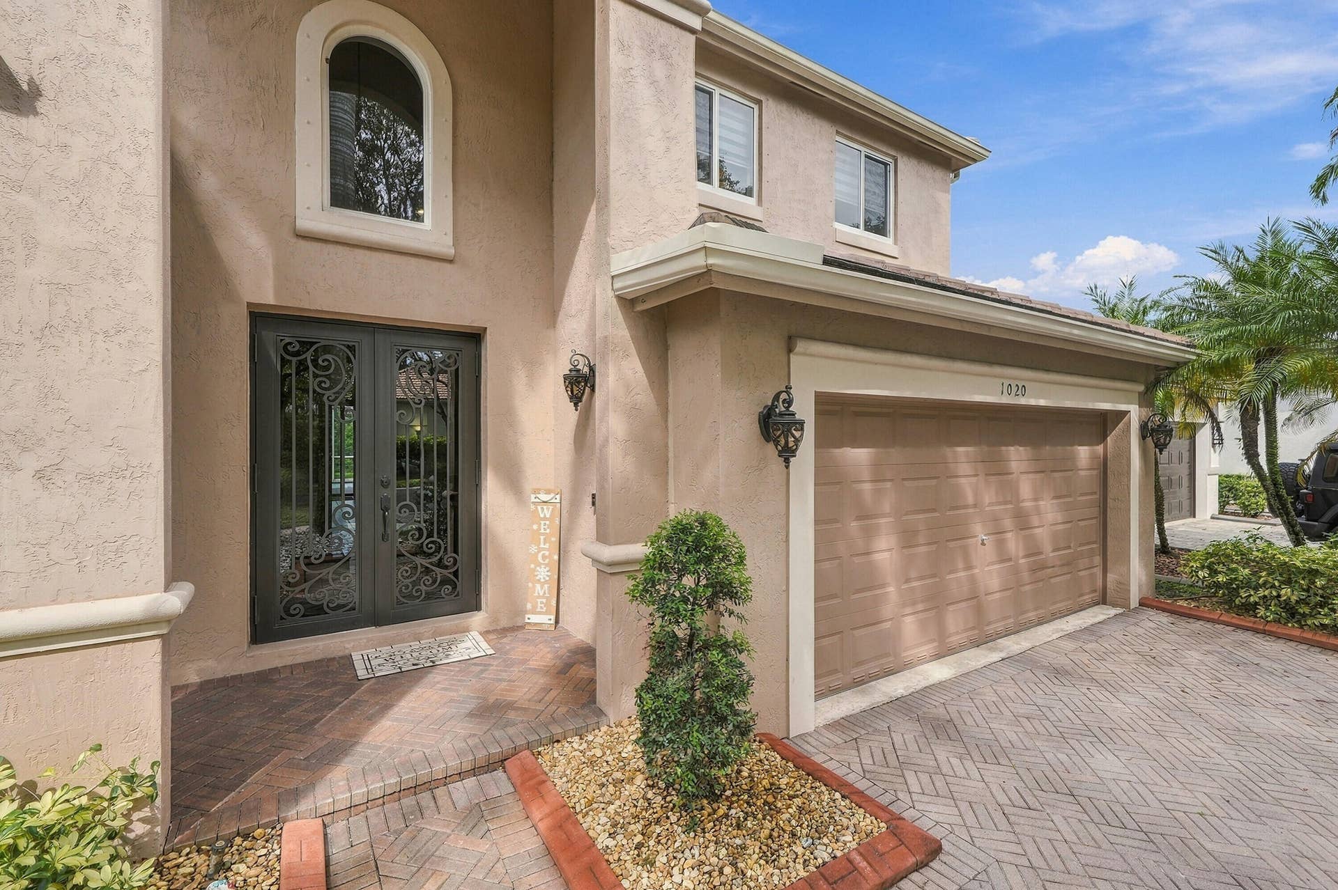 1020 Lavender Circle, Weston, FL 33327 Stucco exterior with an arched window, decorative double entry doors, an attached garage, and a paver driveway