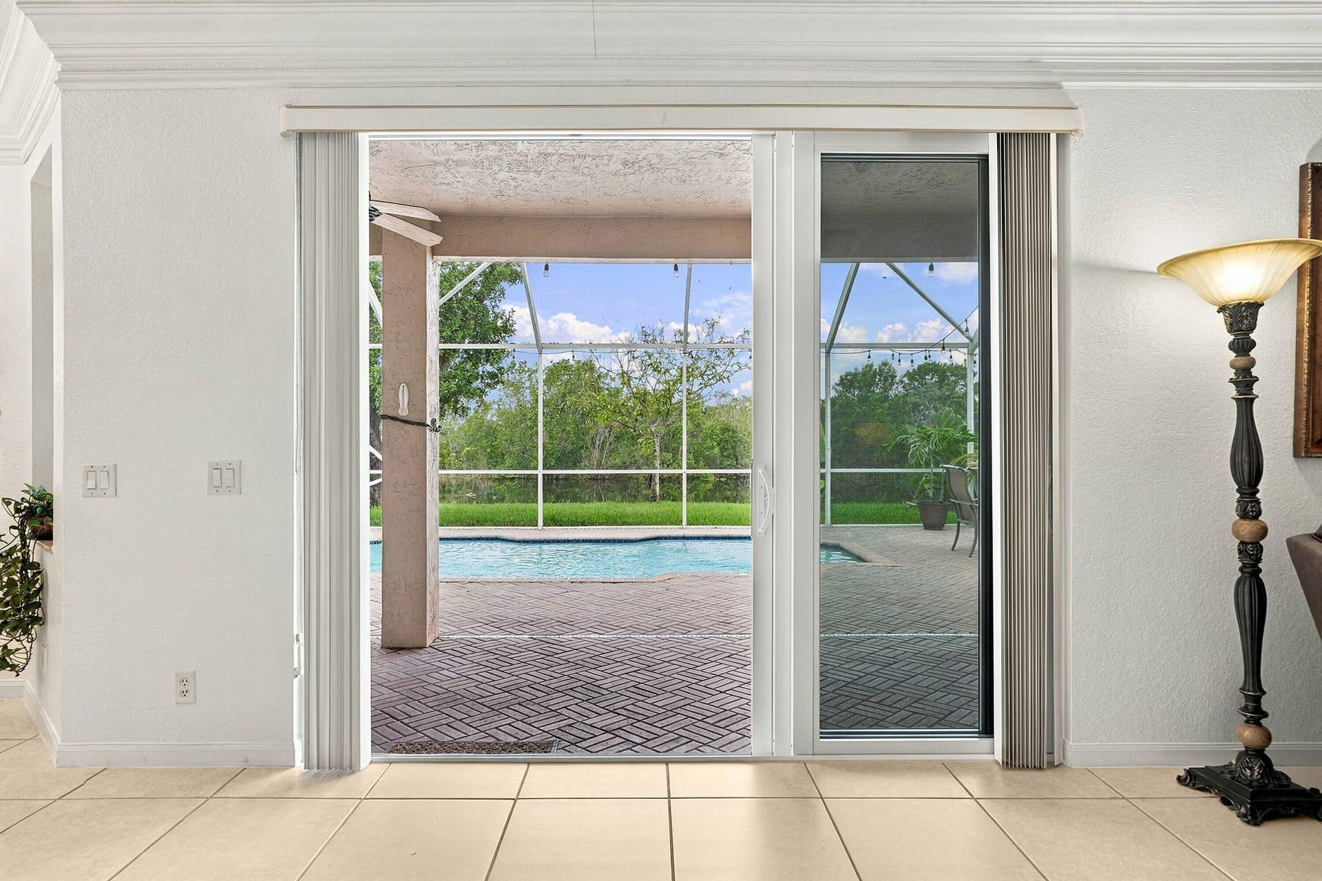 1020 Lavender Circle, Weston, FL 33327 Sliding glass doors opening to a screened-in lanai with a swimming pool, surrounded by paver patio