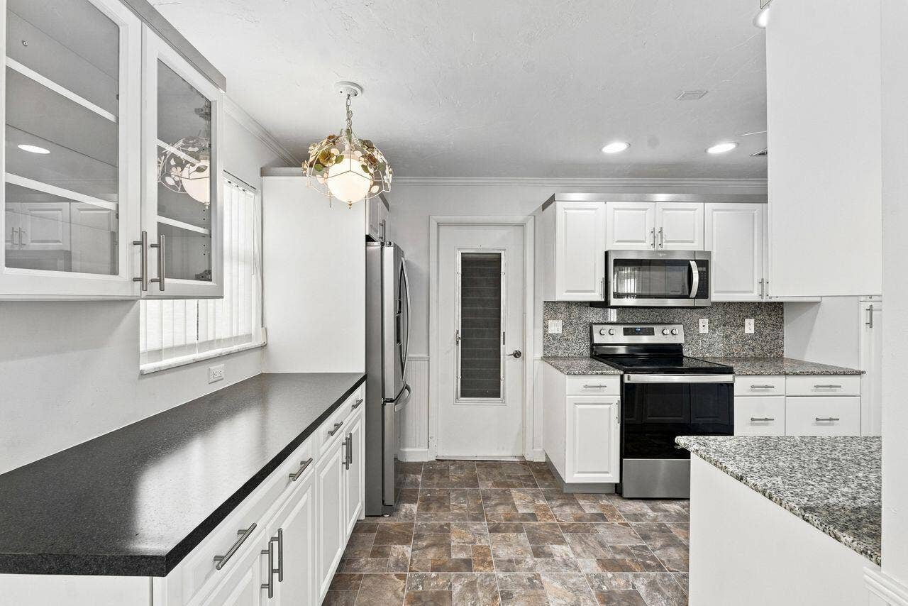 1003 SW 17th Street, Boynton Beach, FL 33426 Kitchen featuring white cabinetry, stainless steel appliances, extra cabinetry with pantry and a tiled backsplash