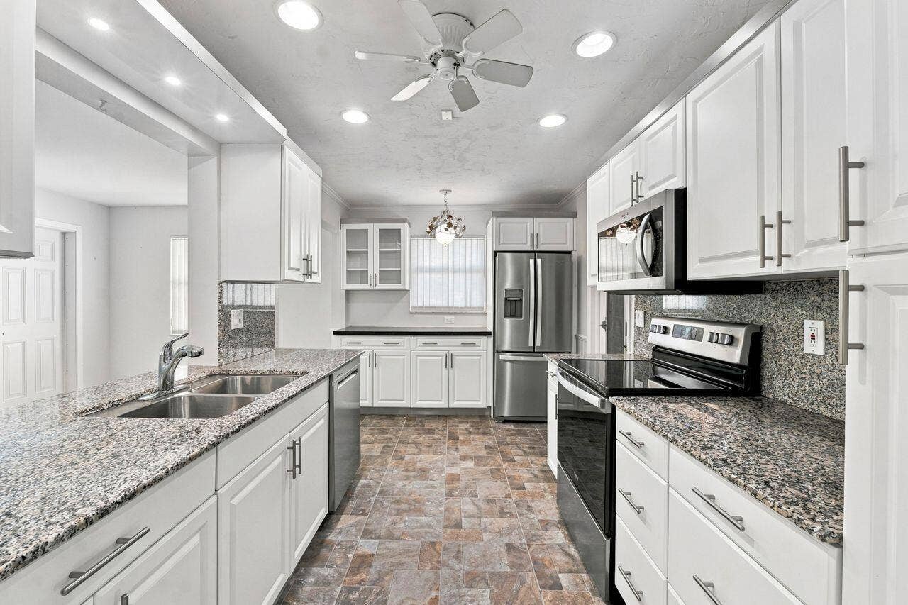 1003 SW 17th Street, Boynton Beach, FL 33426 Kitchen featuring white cabinetry, granite countertops, stainless steel appliances, and recessed lighting