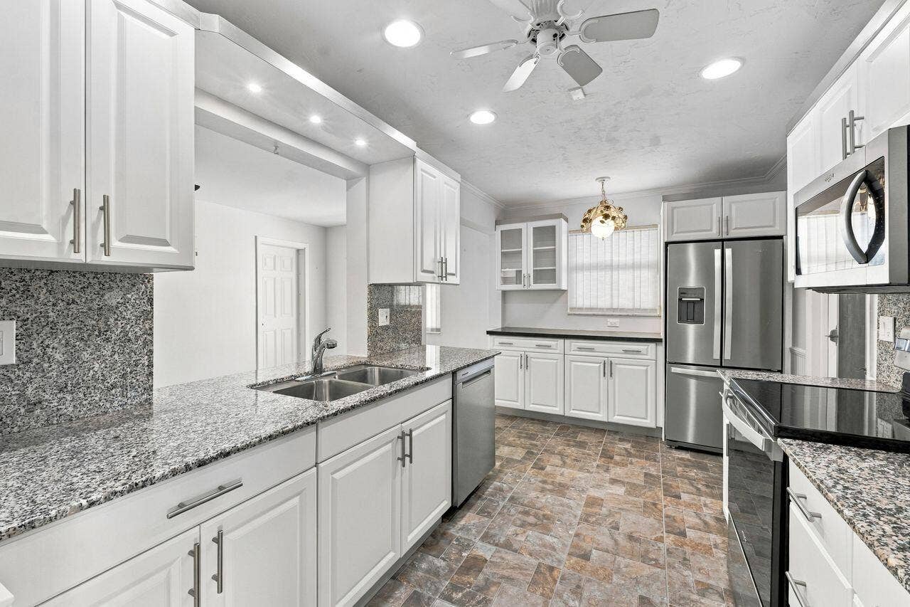 1003 SW 17th Street, Boynton Beach, FL 33426 White shaker-style cabinetry with brushed nickel hardware, stainless steel appliances, granite countertops, and recessed lighting