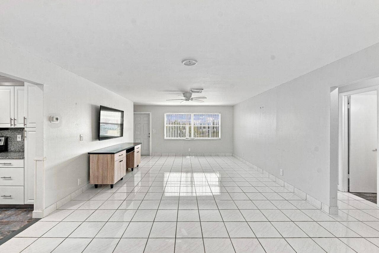 1003 SW 17th Street, Boynton Beach, FL 33426 Expansive open-concept living area featuring white tile flooring, light and bright with a custom TV cabinet and wall mounted TV