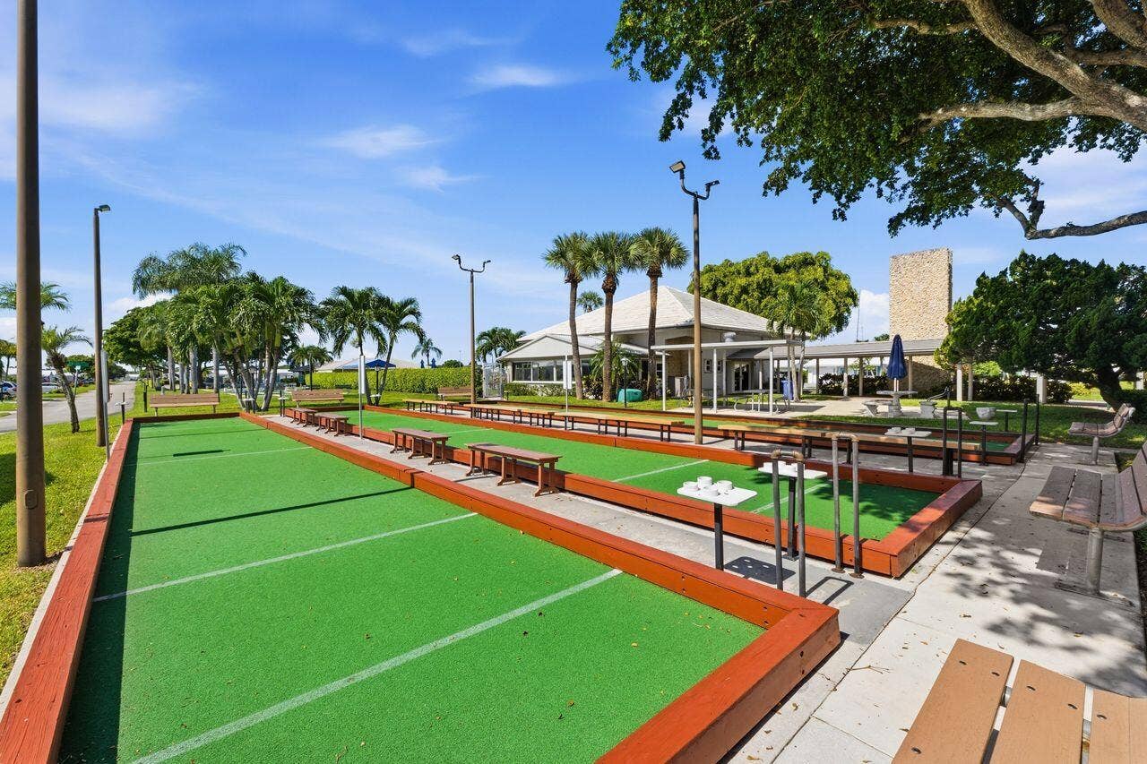 1003 SW 17th Street, Boynton Beach, FL 33426 Bocce ball courts with synthetic turf surfaces, bordered by wood-finish retaining walls and integrated seating