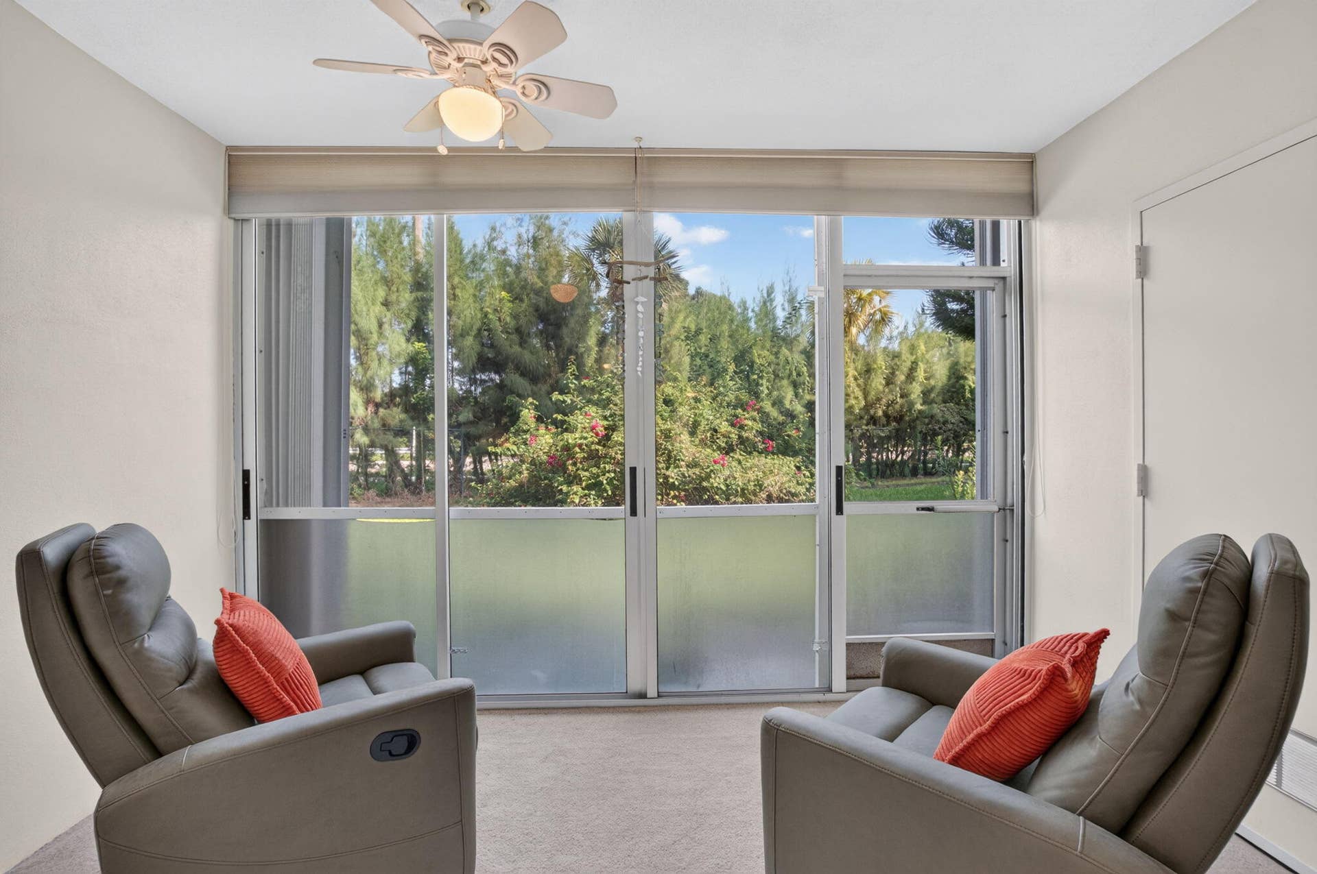 2320 SW 22nd Avenue, #211, Delray Beach, FL 33445 Sliding glass doors opening to outdoor greenery, featuring a lighted ceiling fan and storage closet