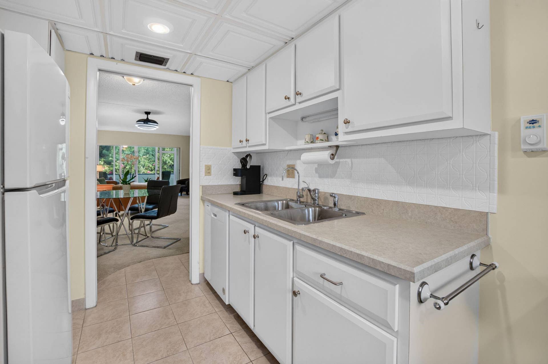 2320 SW 22nd Avenue, #211, Delray Beach, FL 33445 Kitchen featuring white cabinetry, a double basin stainless steel sink, light-toned countertops, and tiled flooring