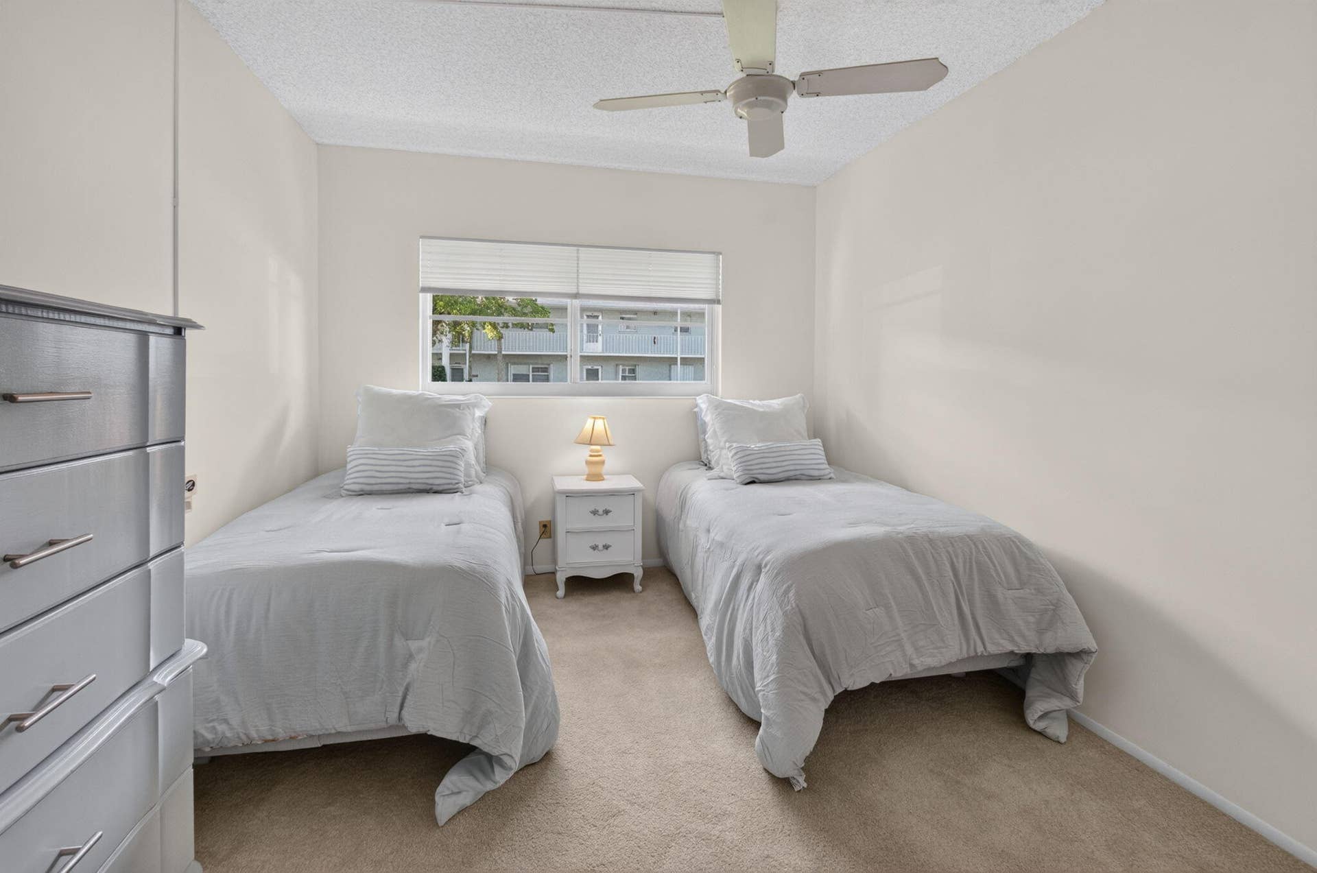 2320 SW 22nd Avenue, #211, Delray Beach, FL 33445 Guest bedroom with twin beds, neutral tone wall paint, carpet flooring, ceiling fan, and window with blinds