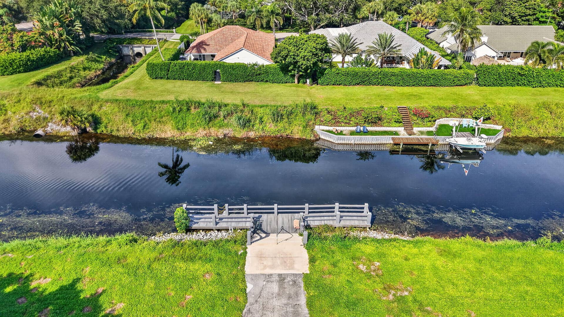 2320 SW 22nd Avenue, #211, Delray Beach, FL 33445 Waterfront property featuring a private dock, additional waterside seating area, and lush green landscaping