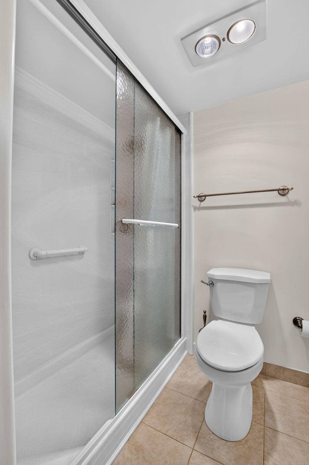 2320 SW 22nd Avenue, #211, Delray Beach, FL 33445 Primary bath with sliding glass door, white shower base, and integrated grab bars