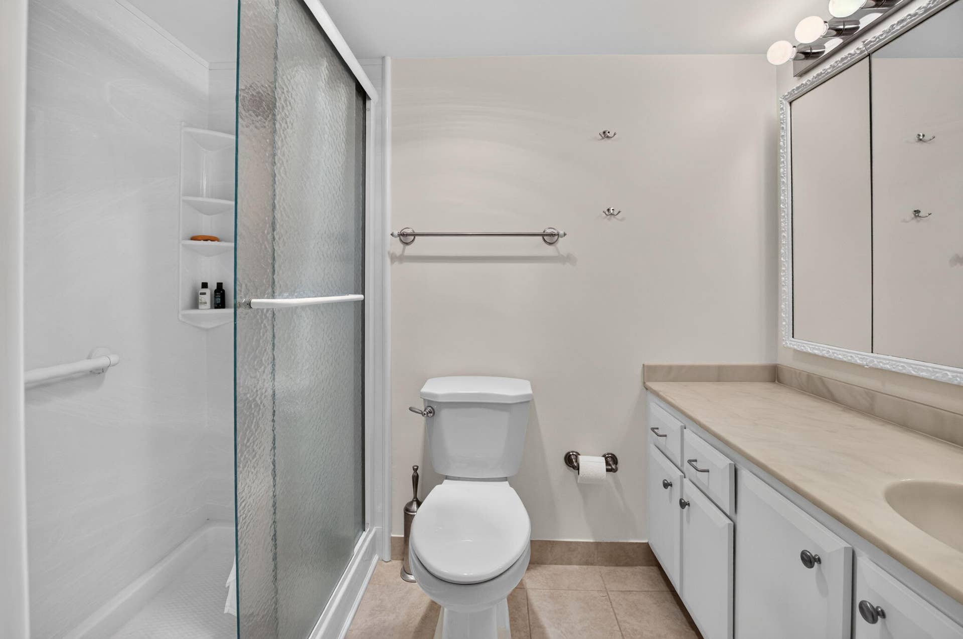 2320 SW 22nd Avenue, #211, Delray Beach, FL 33445 Primary bath with shower with sliding glass doora and grab bars, white vanity with ample storage, light-colored countertop, and tiled flooring