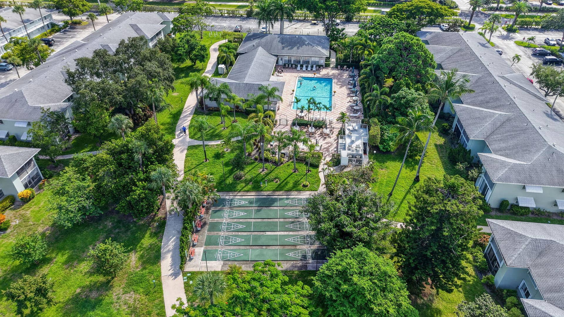 2320 SW 22nd Avenue, #211, Delray Beach, FL 33445 Community featuring a central swimming pool, multiple shuffleboard courts, extensive green spaces, and mature landscaping