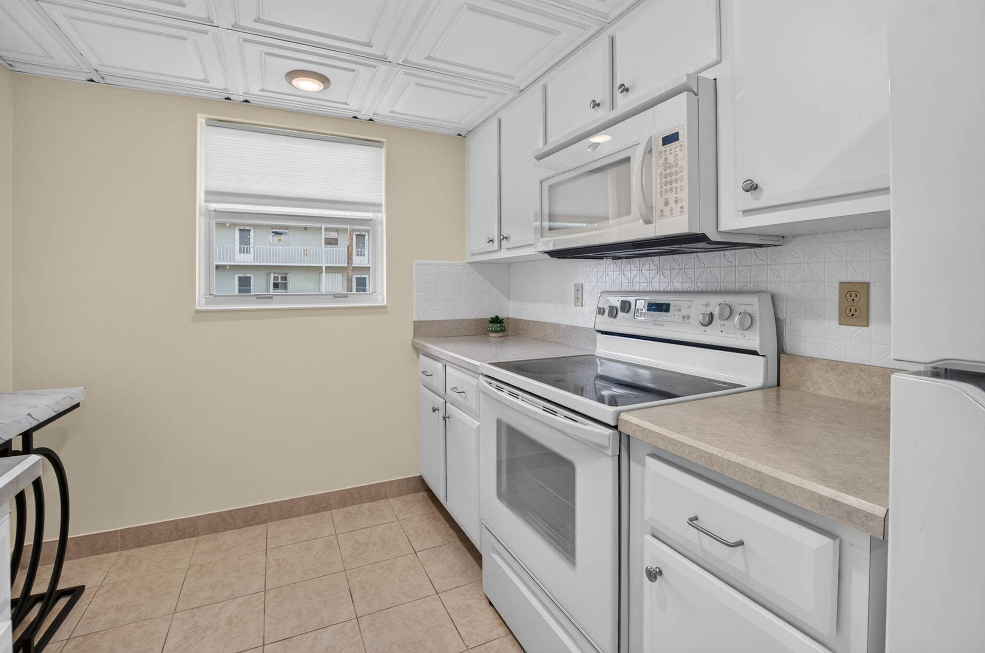 2320 SW 22nd Avenue, #211, Delray Beach, FL 33445 Kitchen featuring white cabinetry, tile flooring, a white electric range, and a white over-the-range microwave