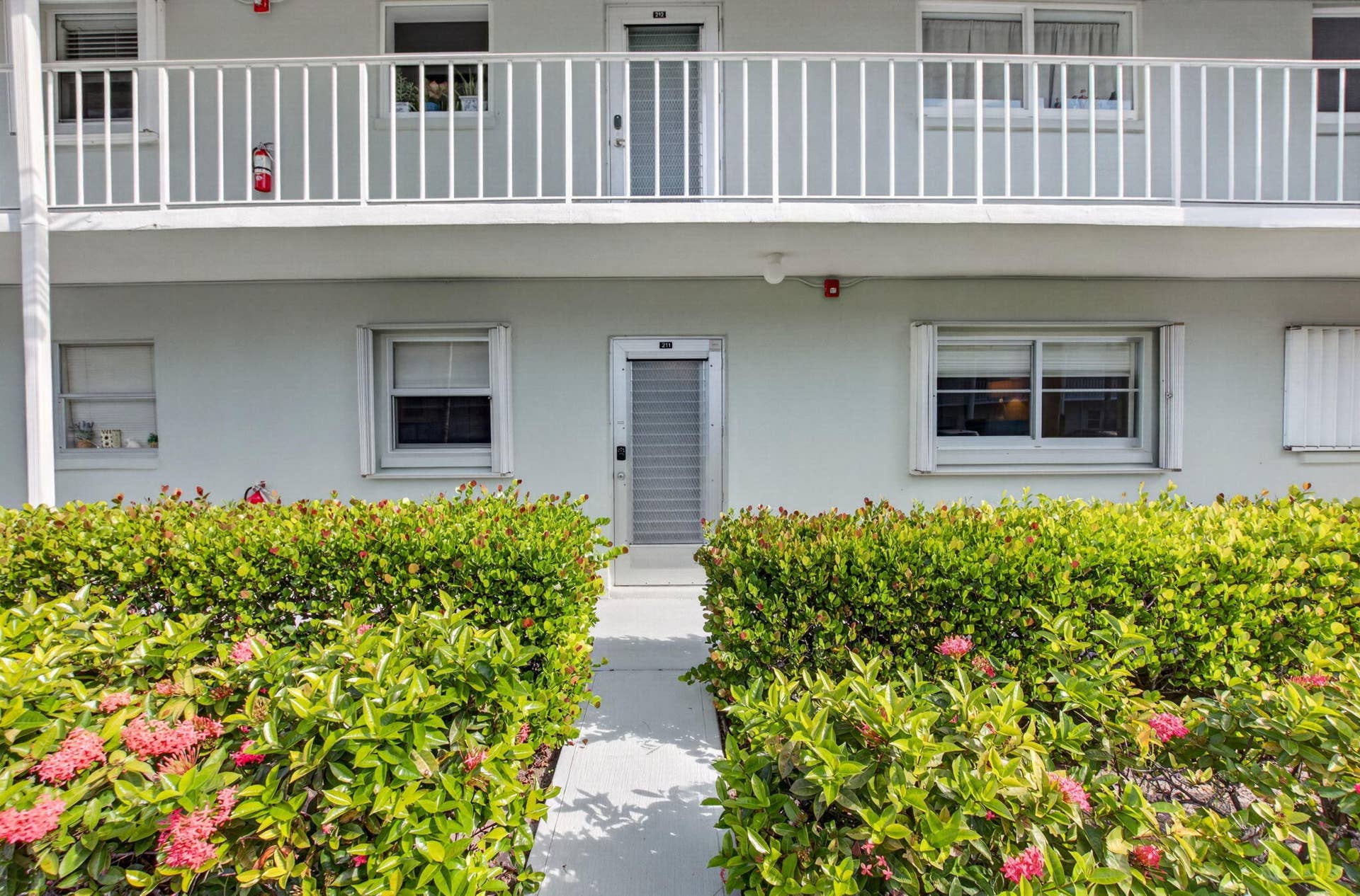 2320 SW 22nd Avenue, #211, Delray Beach, FL 33445 Exterior featuring ground-level entrance with a covered walkway, and mature landscaping with flowering shrubs