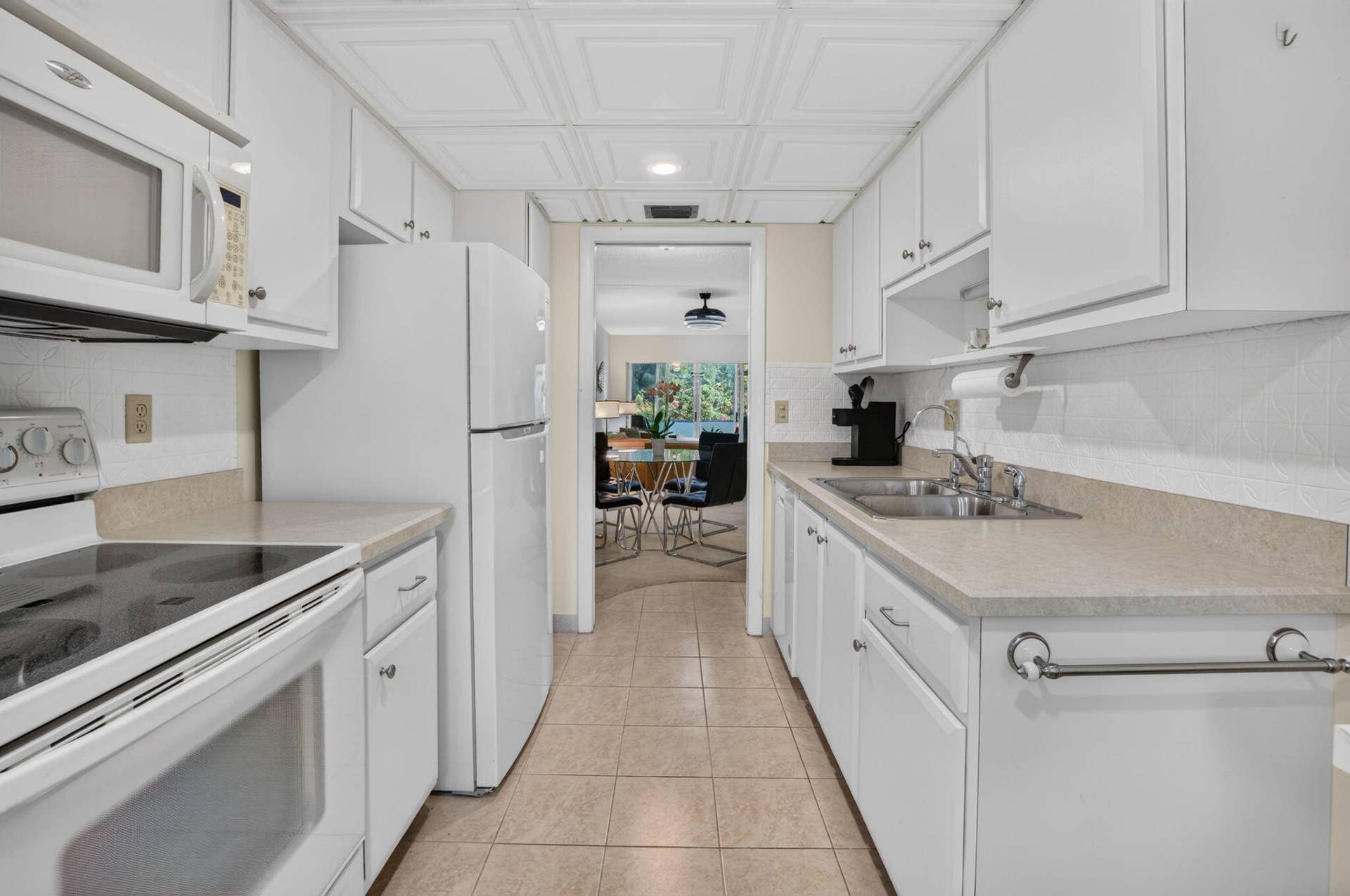 2320 SW 22nd Avenue, #211, Delray Beach, FL 33445 Galley kitchen featuring white cabinetry, light-toned countertops, and tile flooring