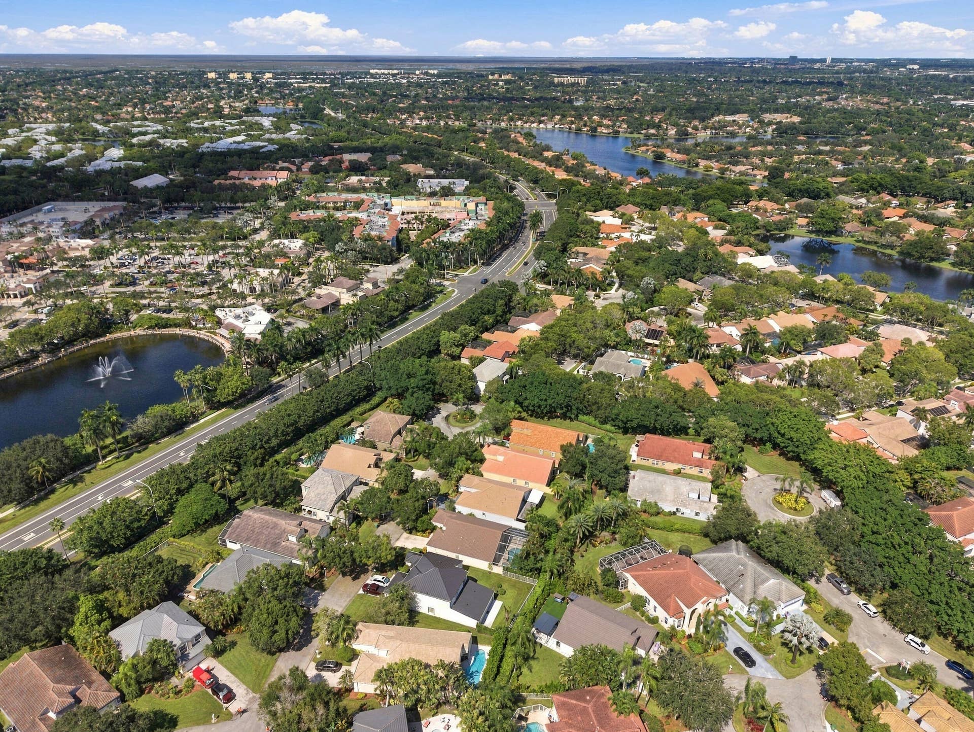 1985 Landing Way, Weston, FL 33326 Aerial perspective showcasing a residential area with varied rooflines, abundant mature trees, multiple water features including lakes with fountains, and an extensive road network