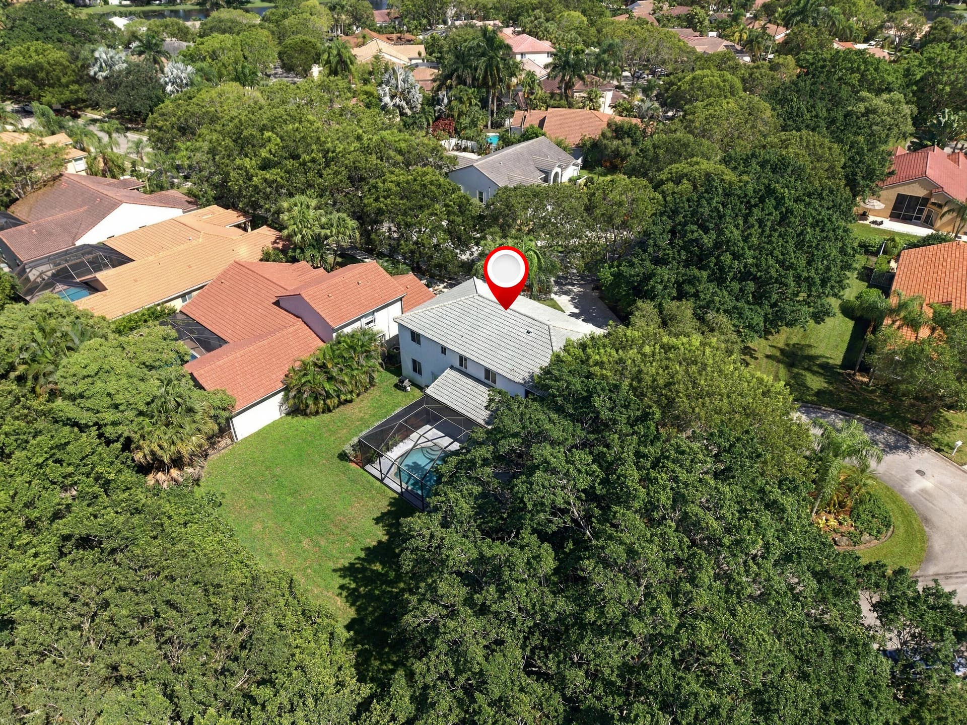 1985 Landing Way, Weston, FL 33326 Two-story residence with a screened-in pool, surrounded by mature trees