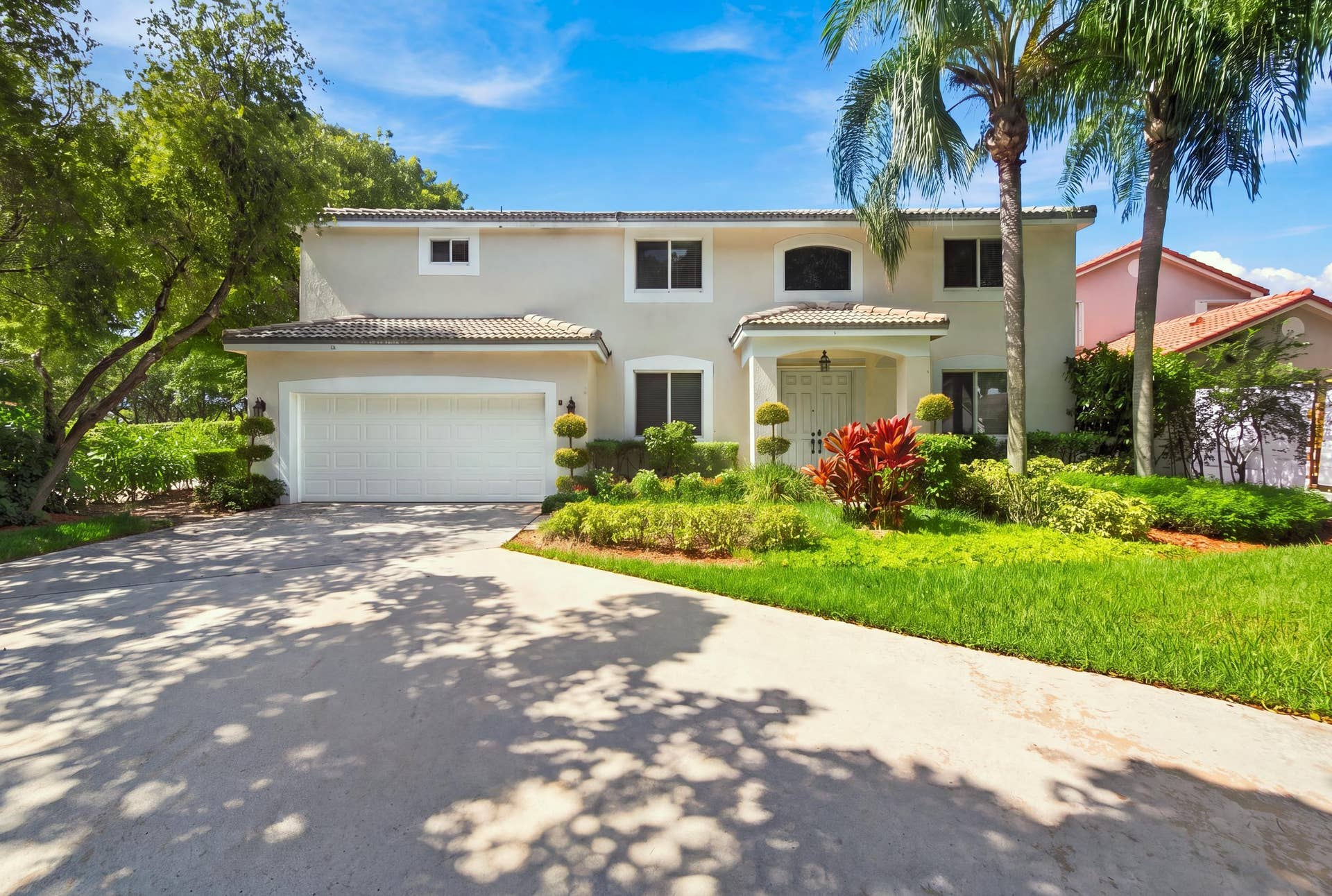 1985 Landing Way, Weston, FL 33326 Stucco exterior with a tiled roof, mature tropical landscaping, a portico entrance, and a two-car garage
