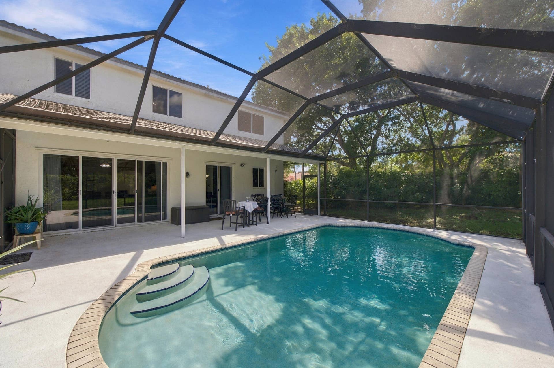 1985 Landing Way, Weston, FL 33326 Screened-in pool area featuring a rectangular pool with curved steps, brick coping, and a surrounding concrete deck