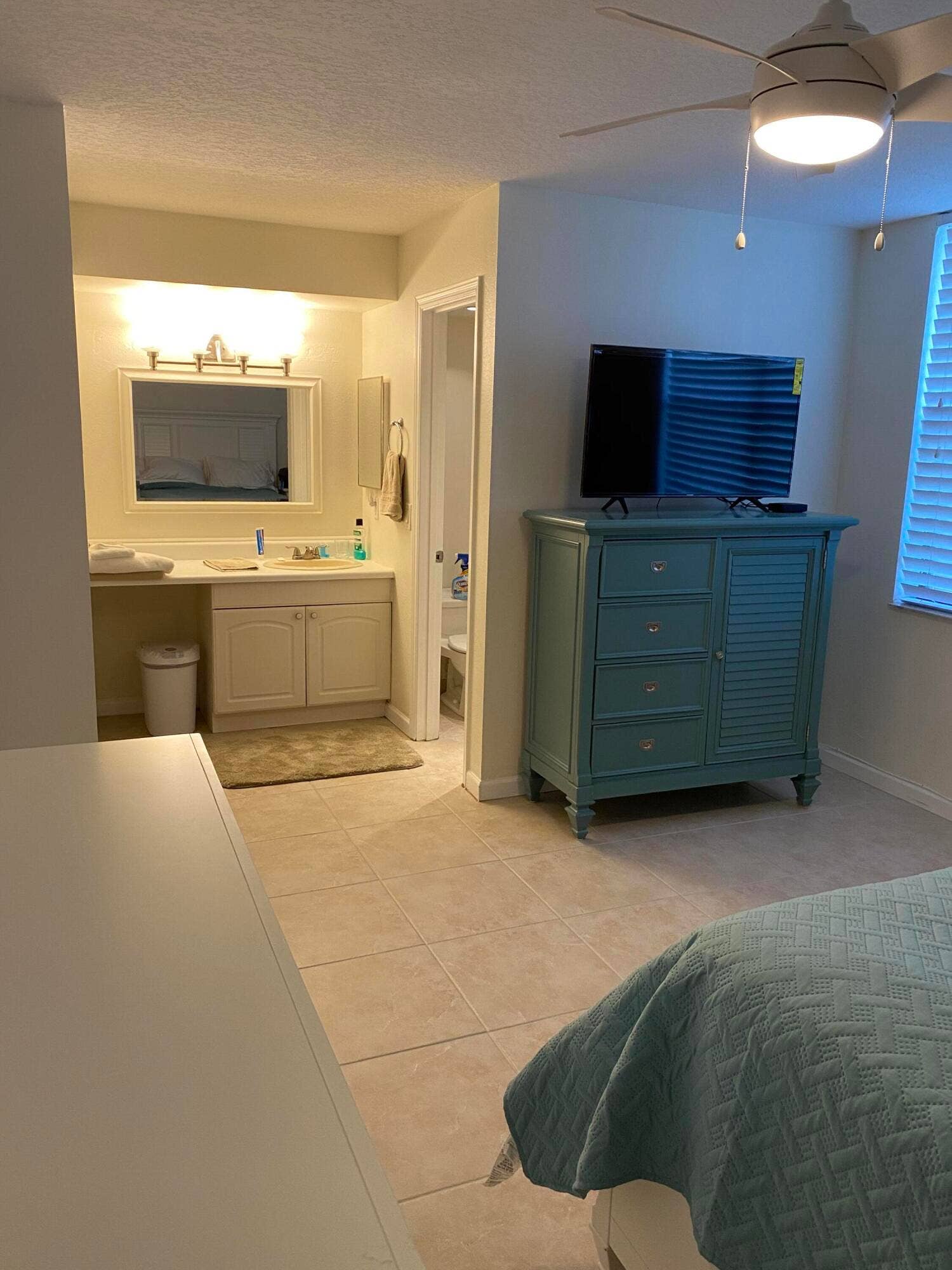 Tile flooring extending into a full bathroom with a vanity and mirror