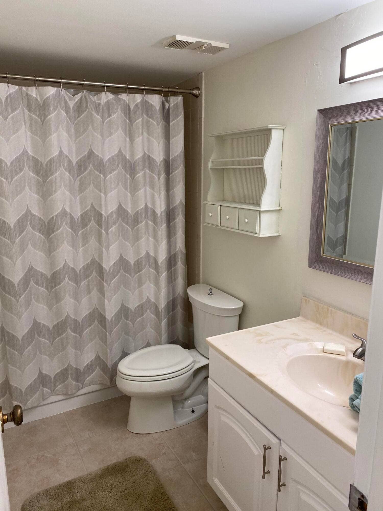 Compact bathroom featuring geometric patterned tile flooring, white subway tile walls, toilet, pedestal sink, and medicine cabinet with mirror