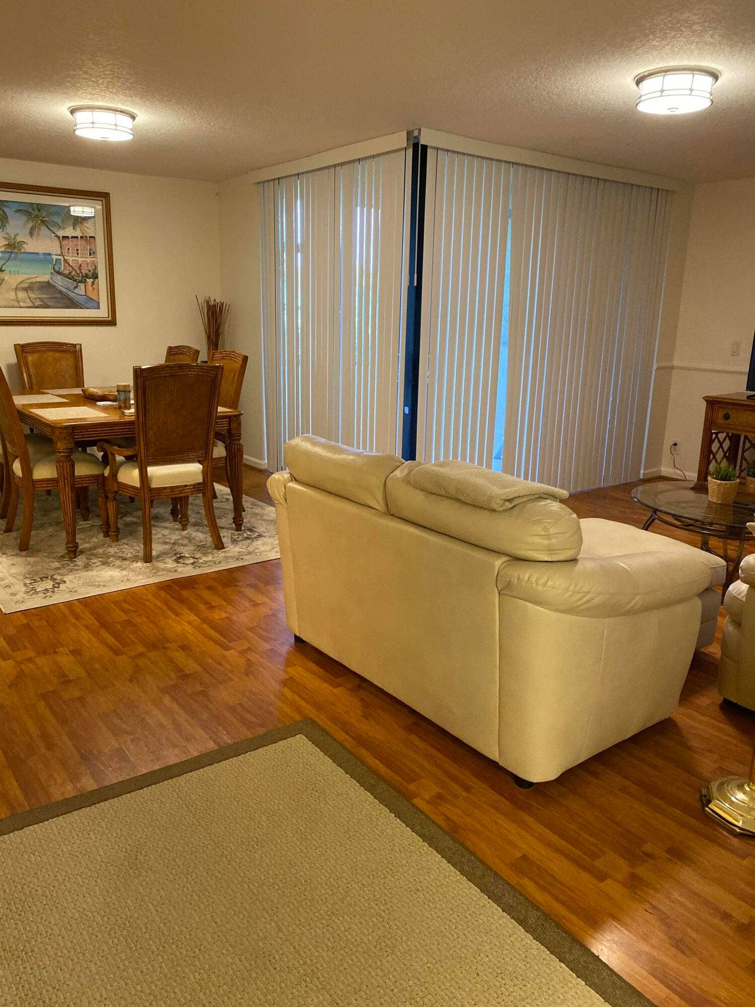 Hardwood-finish flooring throughout, featuring a large window with horizontal blinds, and recessed lighting