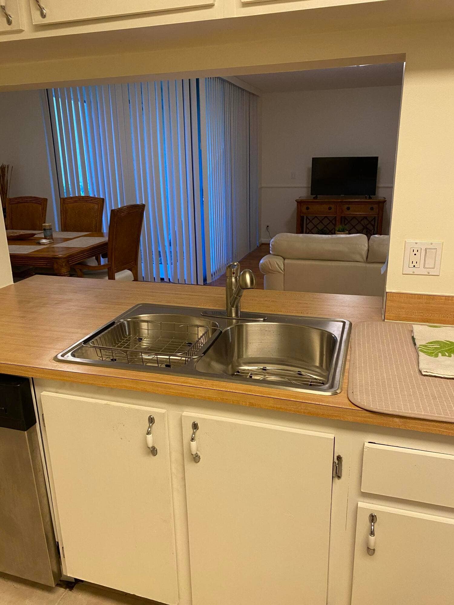 Kitchen featuring a stainless steel double-basin sink, laminate countertops, and white cabinetry