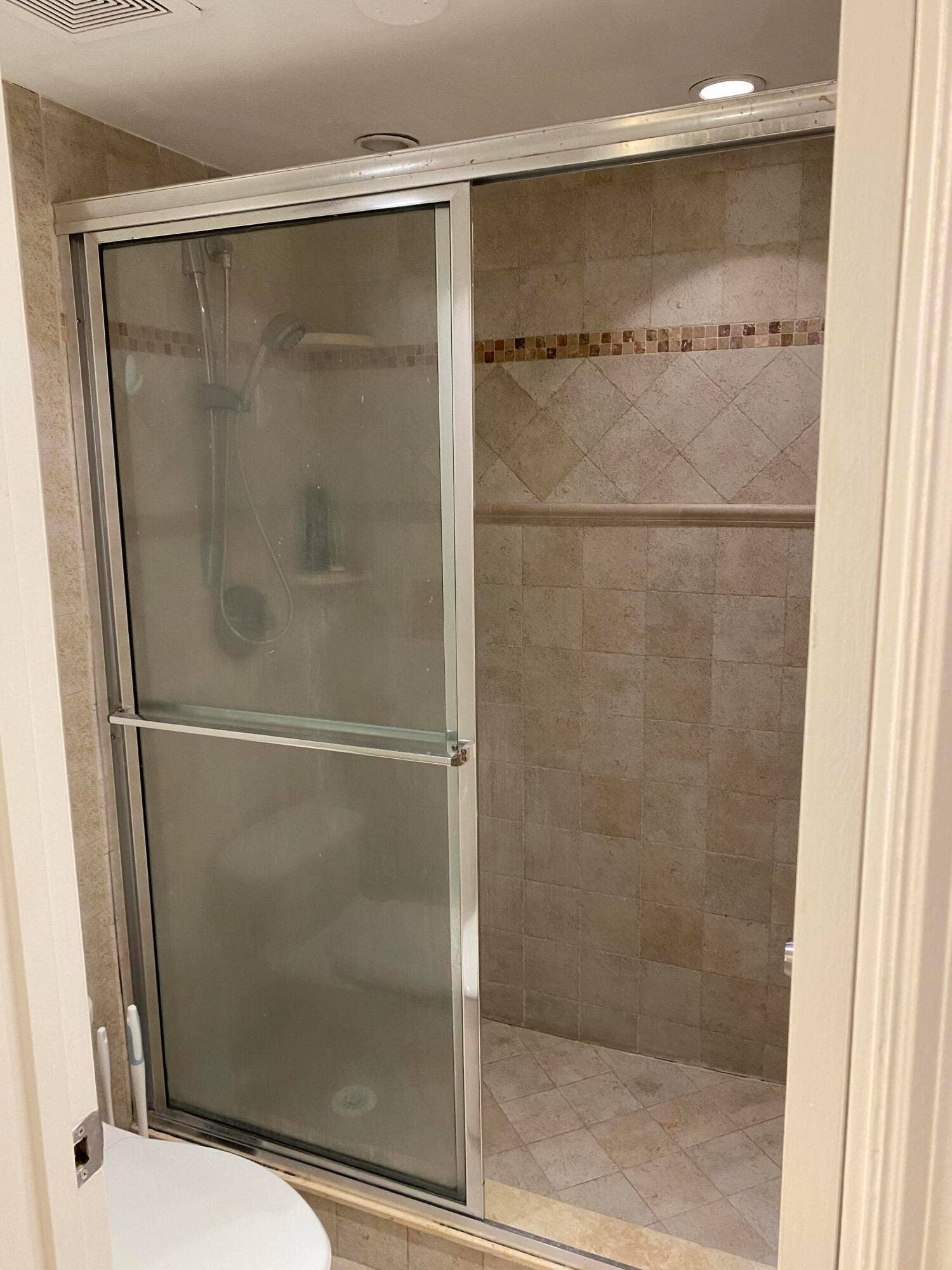 Enclosed shower with tiled walls and decorative accent band