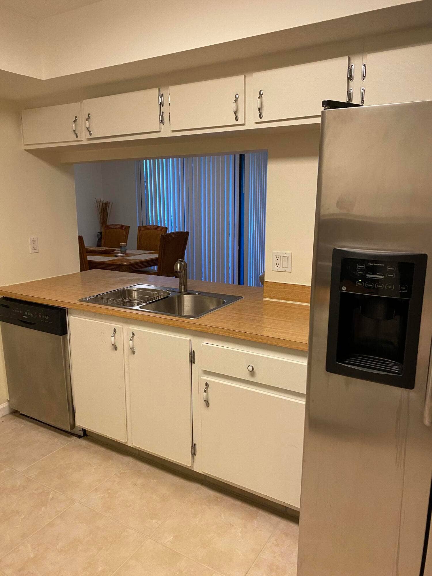 Kitchen featuring white cabinetry, wood-finish countertops, and a stainless steel refrigerator with an external dispenser