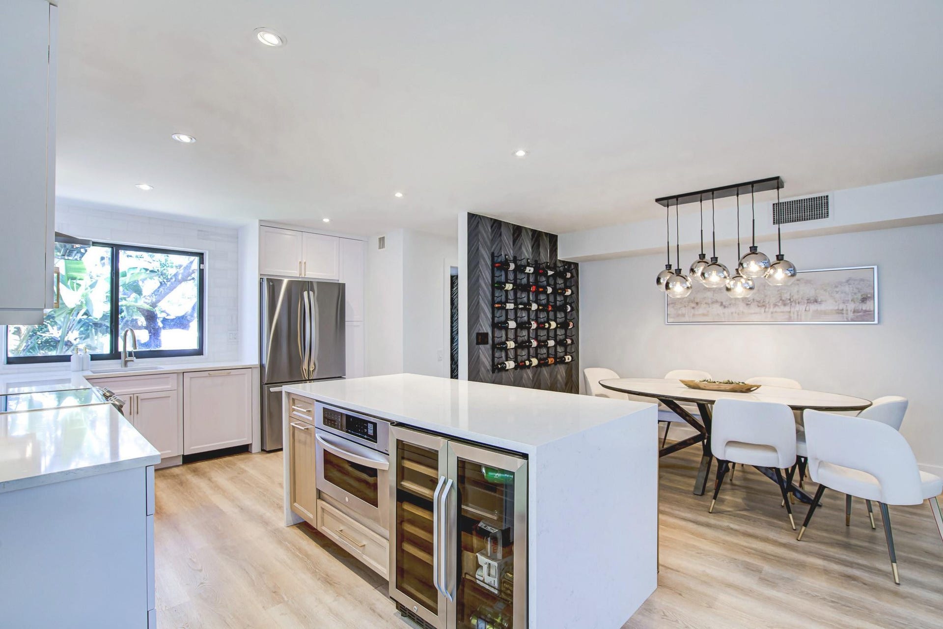 Kitchen featuring a large central island with integrated wine refrigeration, wood-finish flooring, stainless steel appliances, and recessed lighting