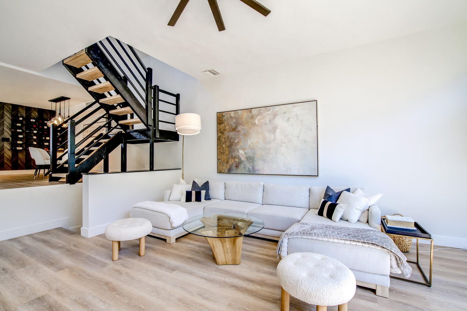 Light wood-finish flooring, a contemporary ceiling fan, and a striking open staircase with black metal railings